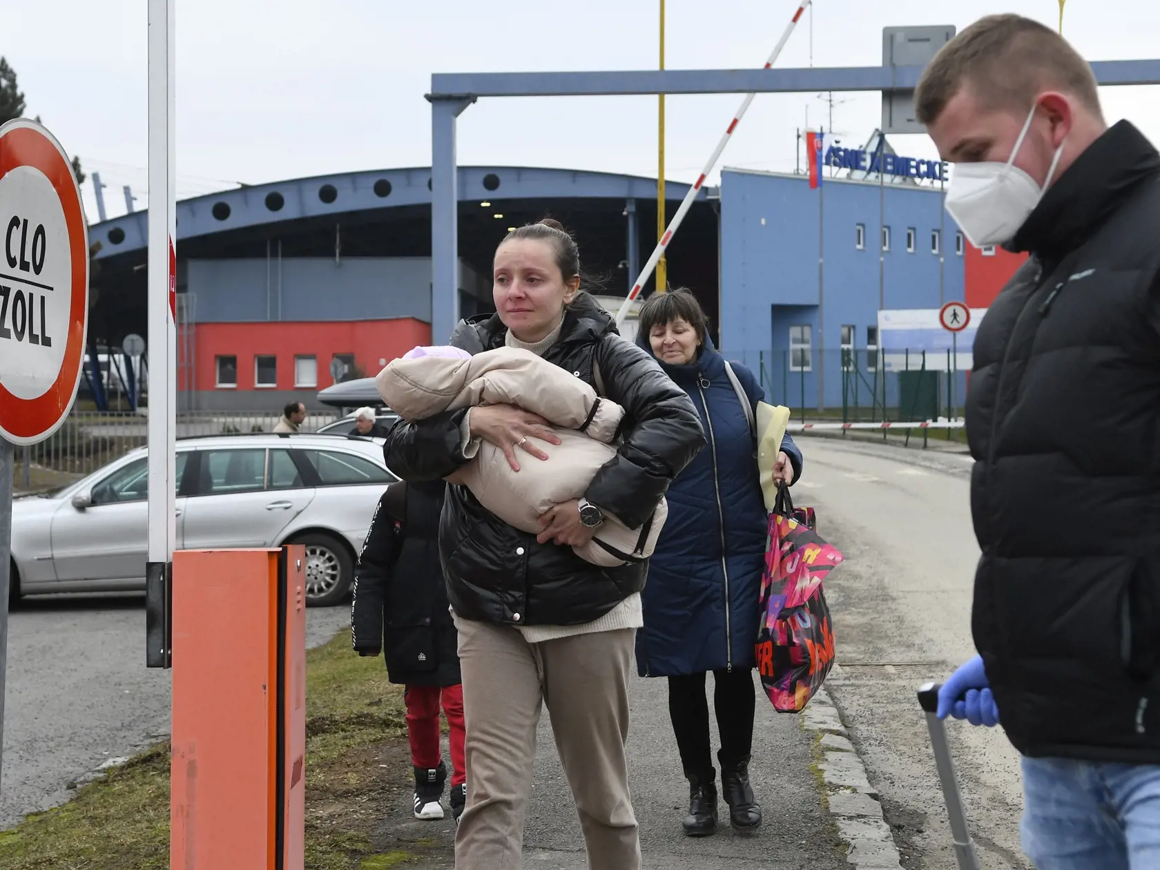 Utečenci z Ukrajiny prechádzajú cez hraničný priechod vo Vyšnom Nemeckom, vpravo im pomáha príslušník finančnej správy.