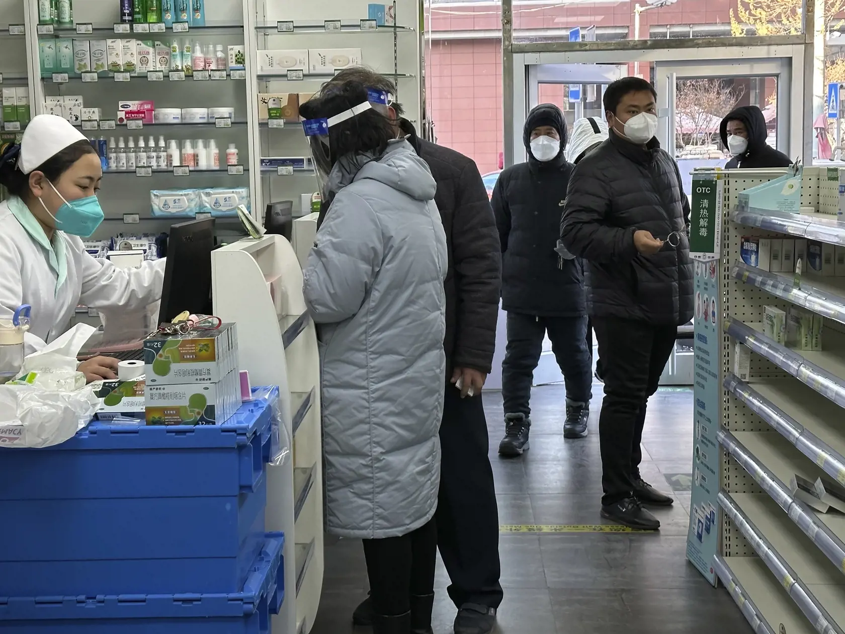 Farmaceutka obsluhuje zákazníčku pri prázdnych regáloch v lekárni, zatiaľčo zákazníci sa pokúšajú nájsť lieky pred ďalšou vlnou ochorenia COVID-19 v čínskom Pekingu 13. decembra 2022. Čína minulý týždeň ohlásila rozsiahle uvoľnenie obmedzení súvisiacich s ochorením COVID-19. Niektorí pozitívni pacienti budú môcť zostať v domácej karanténe a obmedzia sa aj požiadavky na povinné PCR testovanie, informuje TASR na základe správy agentúry AFP.