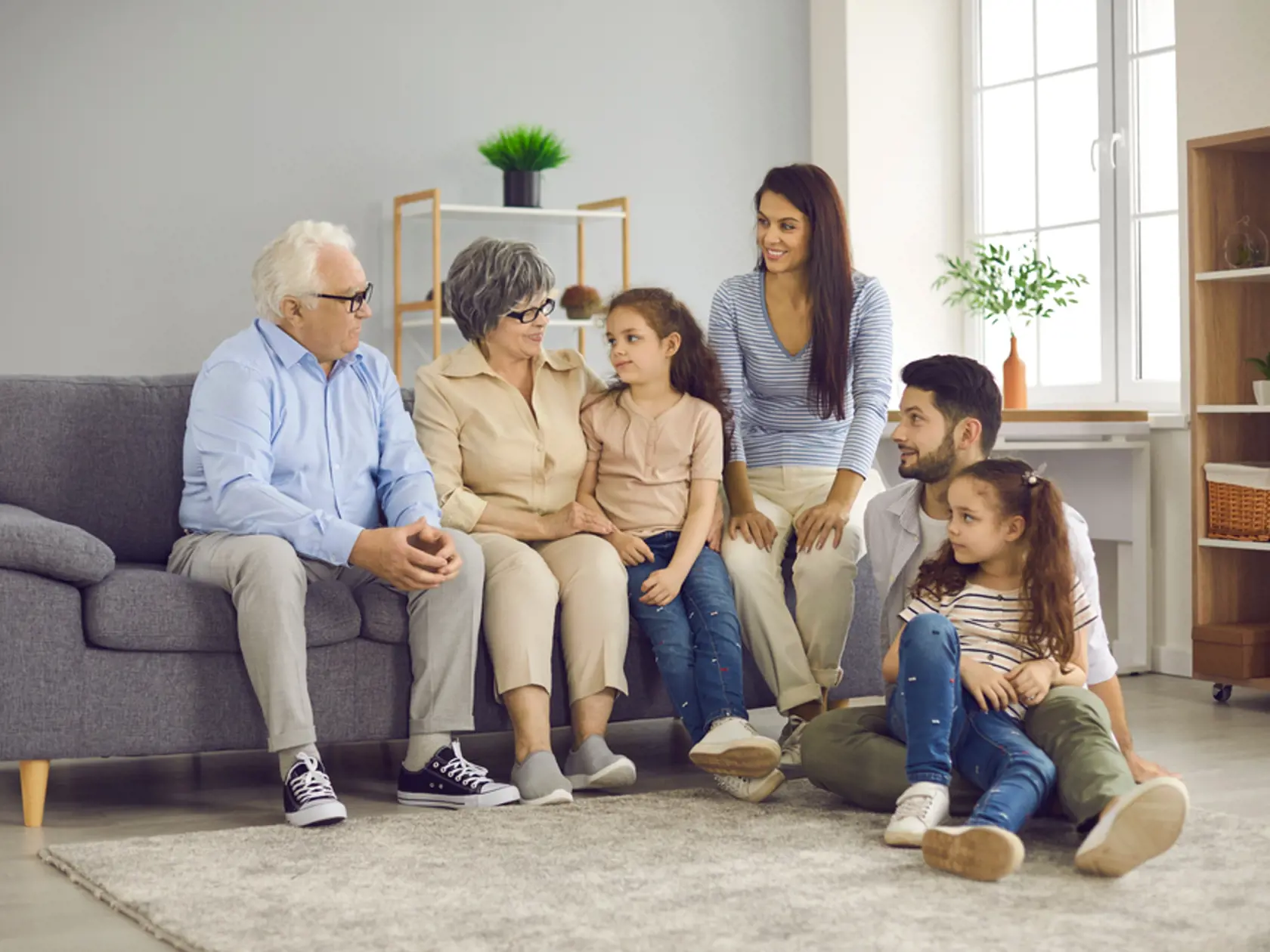 Multi-generation family sitting on sofa in living room. Portrait of a big happy family consisting of grandparents, their children and grandchildren. Family meetings and emotional communication.