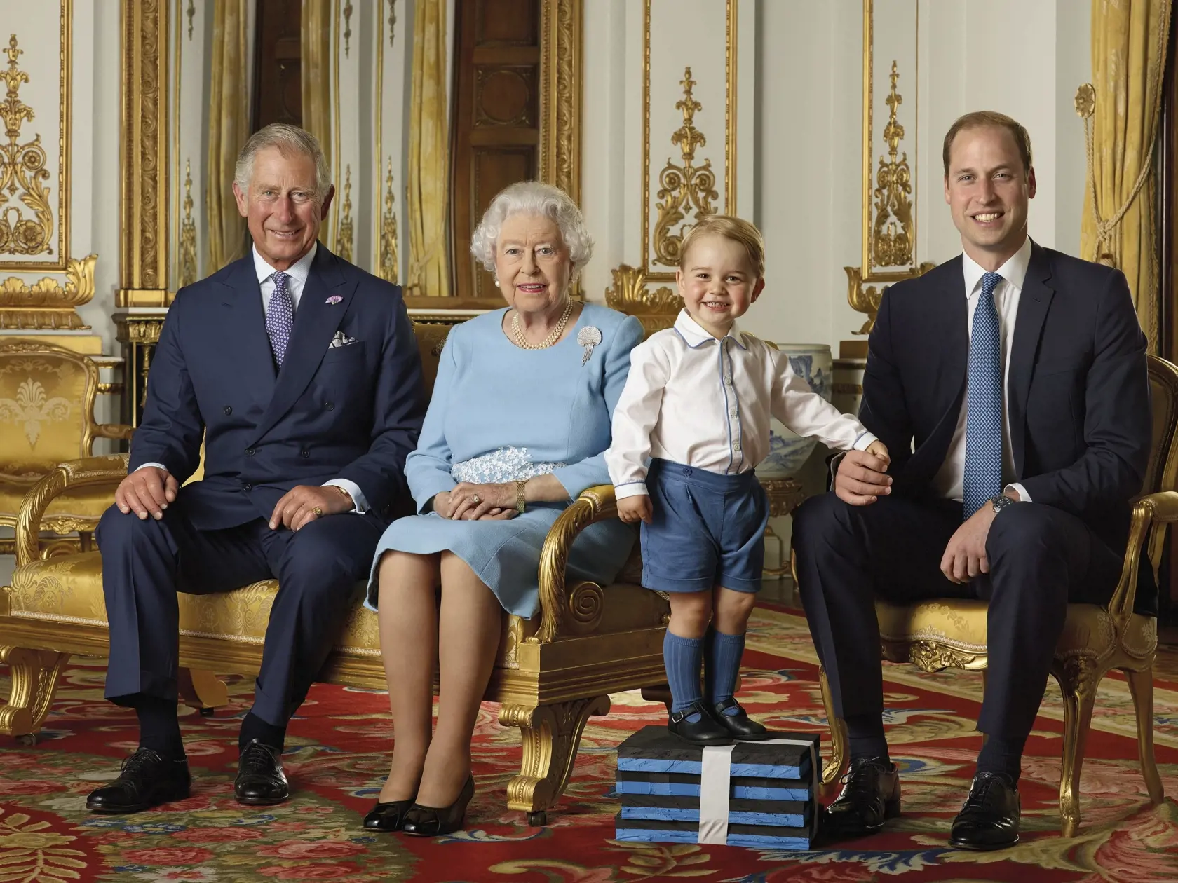 Na snímke, ktorú zverejnila Kráľovská pošta je počas leta 2015 zľava princ Charles, kráľovná Alžbeta II., princ George a princ Villiam - štyri generácie Britskej kráľovskej rodiny v honosnom Bielom salóne Buckinghamského paláca v Londýne.
