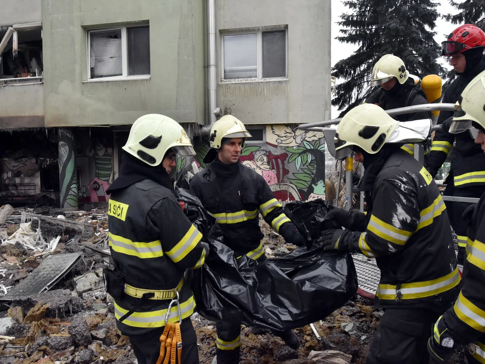 Hasiči nesú z trosiek panelového domu na Mukačevskej ulici v Prešove telesné pozostatky jednej z obetí ničivého výbuch plynu v sobotu 7. decembra 2019. FOTO TASR - Vladimír Benko/MV SR