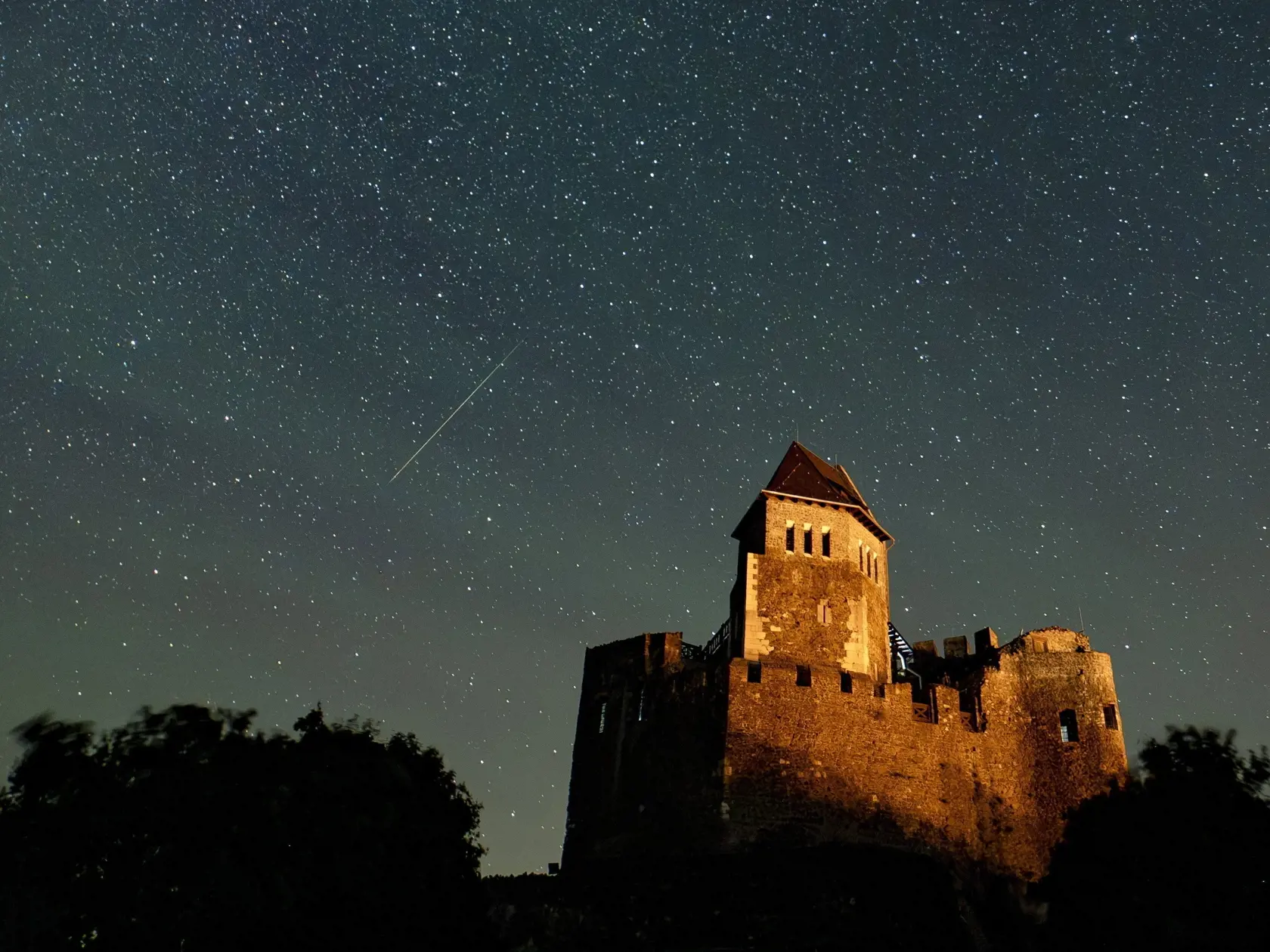KK24 Hollókő - Na snímke meteorický roj Perzeíd nad hradom v maďarskej obci Hollókő vzdialenej 100 km severovýchodne od Budapešti v nedeľu ráno 13. augusta 2023.