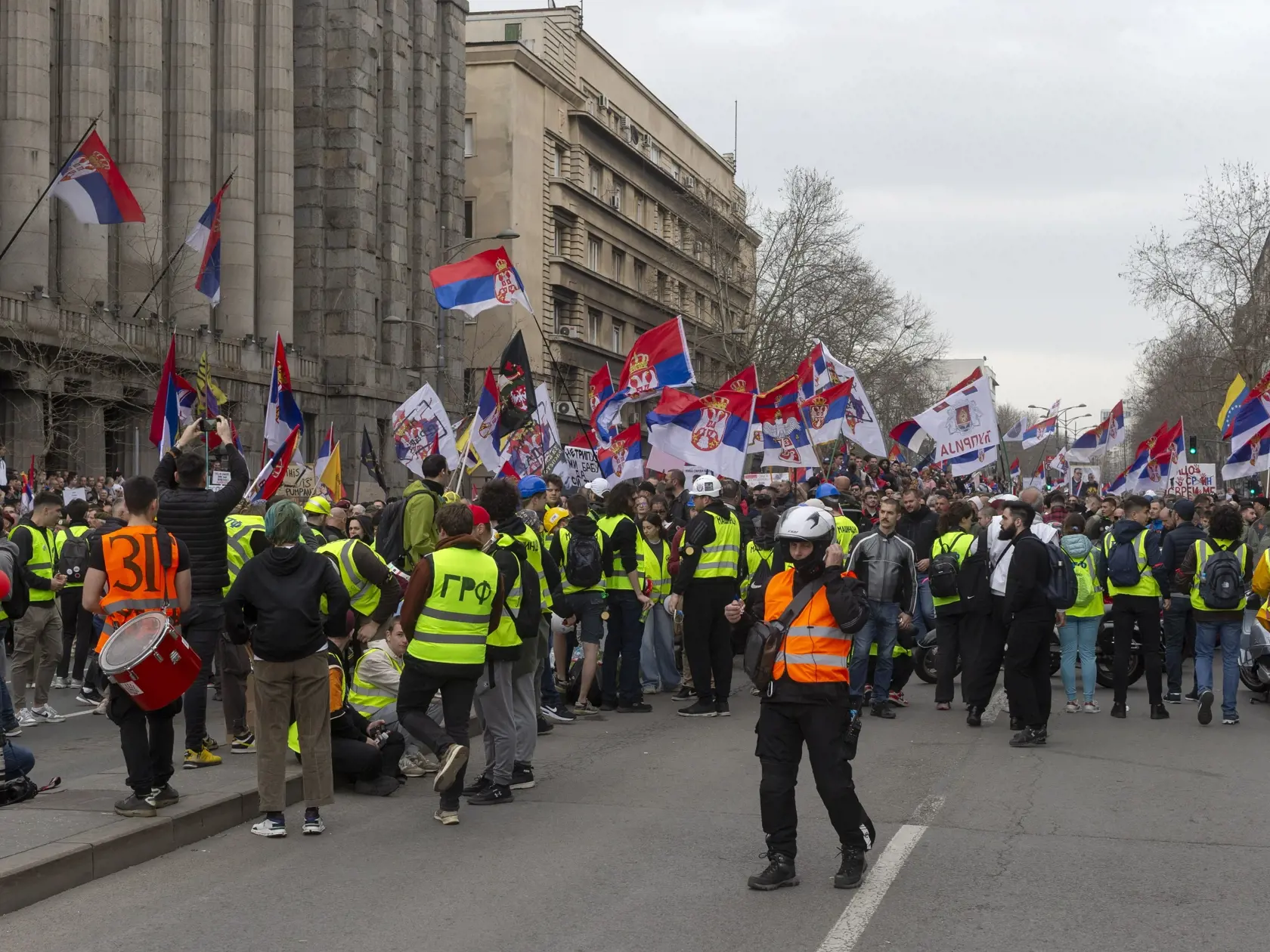 Demonštranti blokujú ulicu a mávajú srbskými zástavami počas veľkého protikorupčného zhromaždenia vedeného univerzitnými študentmi v Belehrade 15. marca 2025.