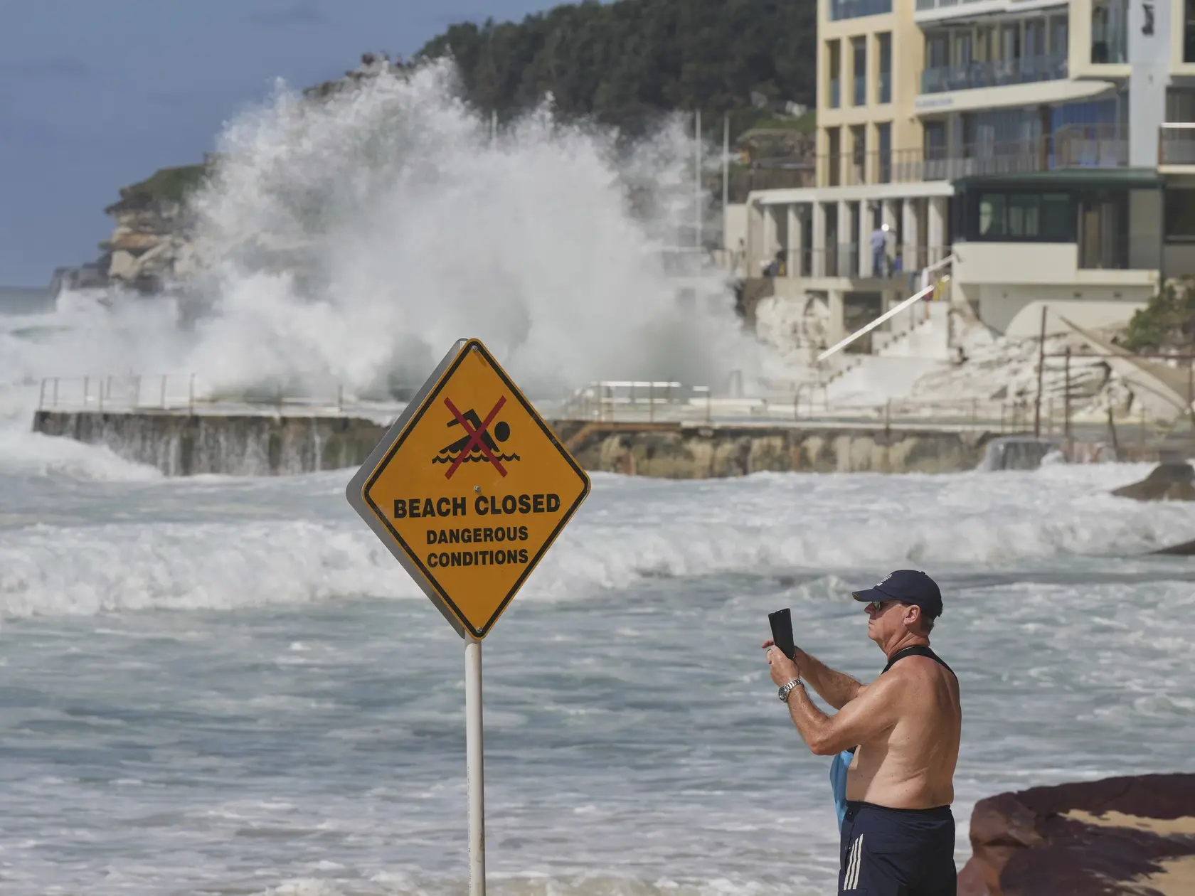 Ľudia sledujú, ako veľké vlny zasiahli pláž Bondi Beach v Sydney.