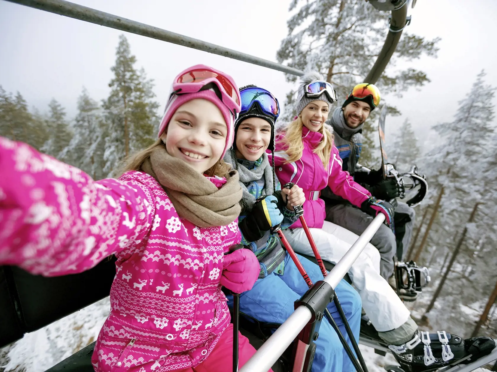 Skiing, ski lift, ski resort - happy smiling family skiers on ski lift making selfie