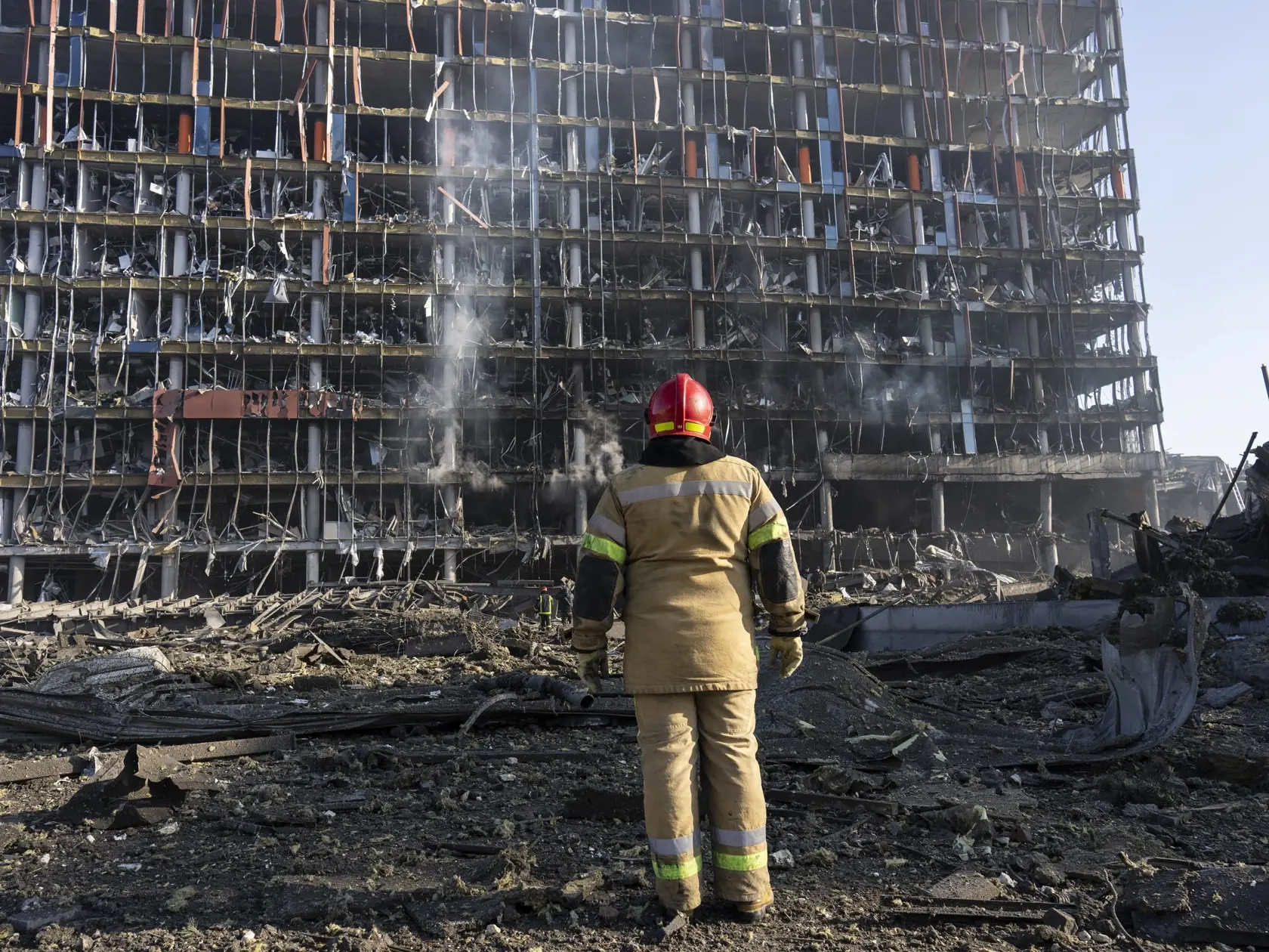 JB 24 Kyjev - Hasič sa pozerá na deštrukciu po ruskom bomardovaní obchodného centra v Kyjeve 21. marca 2022.