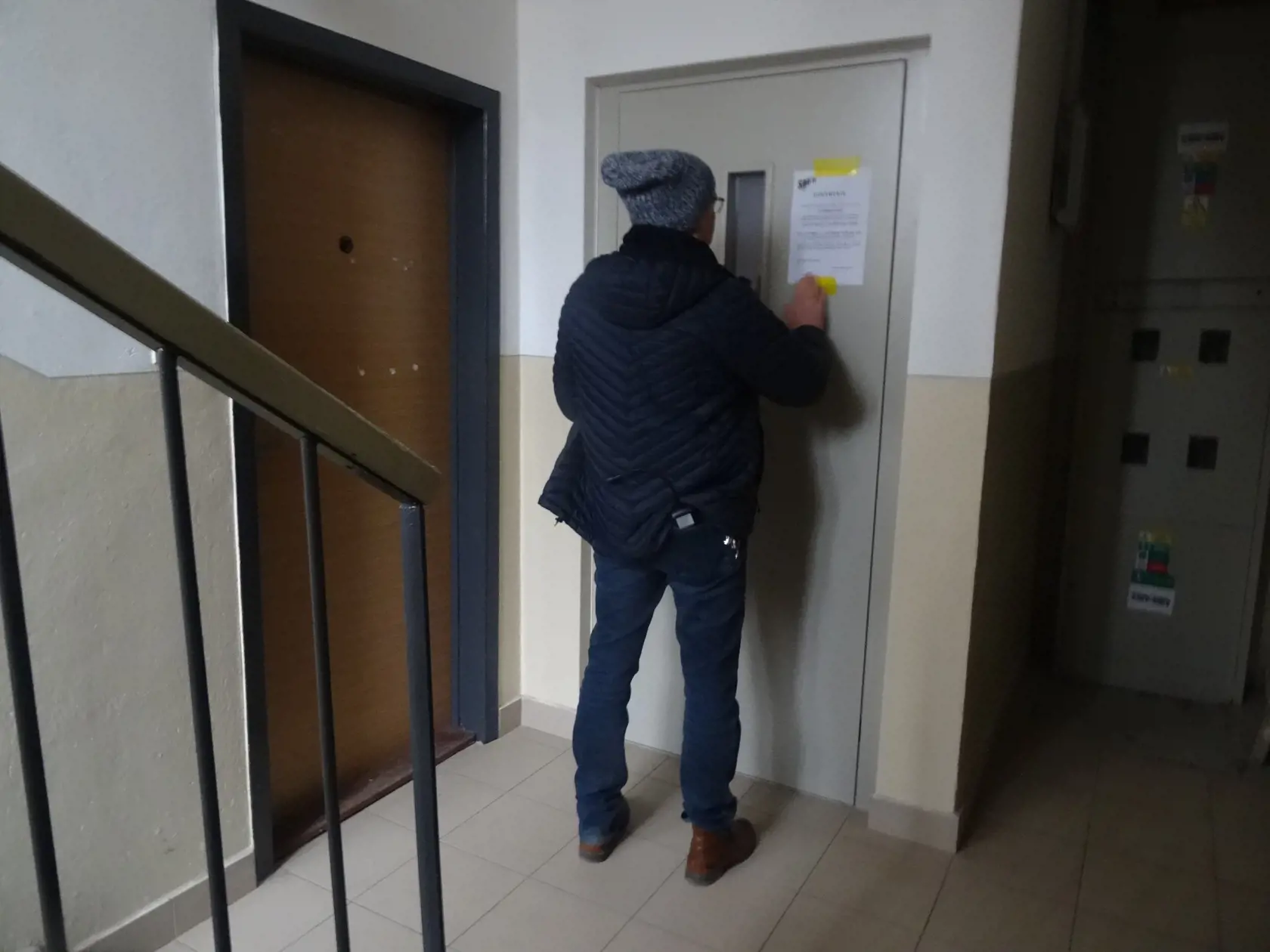 Pracovník dodávateľskej firmy lepí nový oznam.