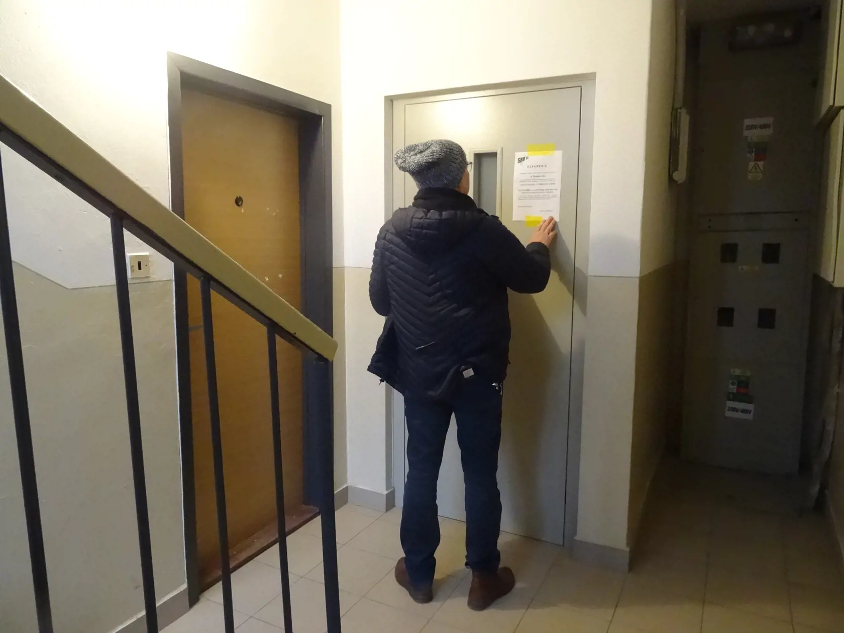 Pracovník dodávateľskej firmy lepí nový oznam.