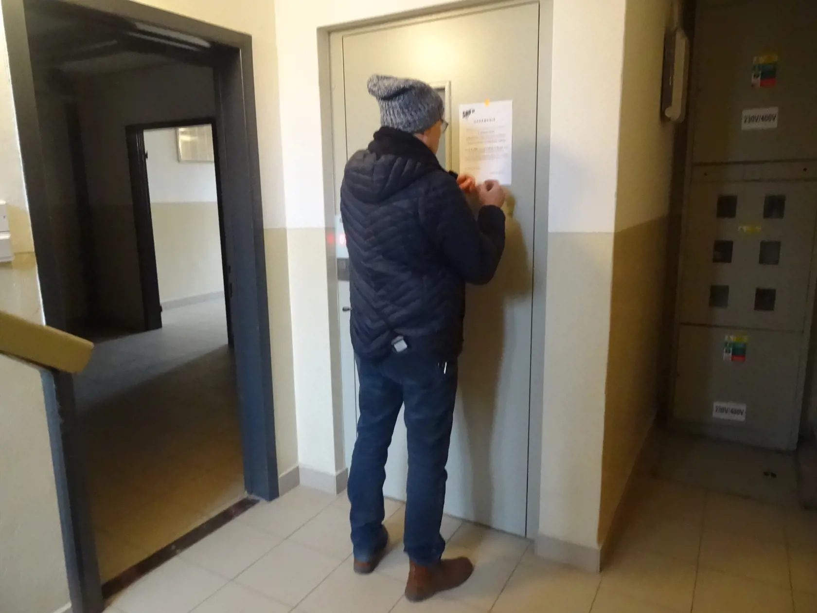 Pracovník dodávateľskej firmy lepí nový oznam.