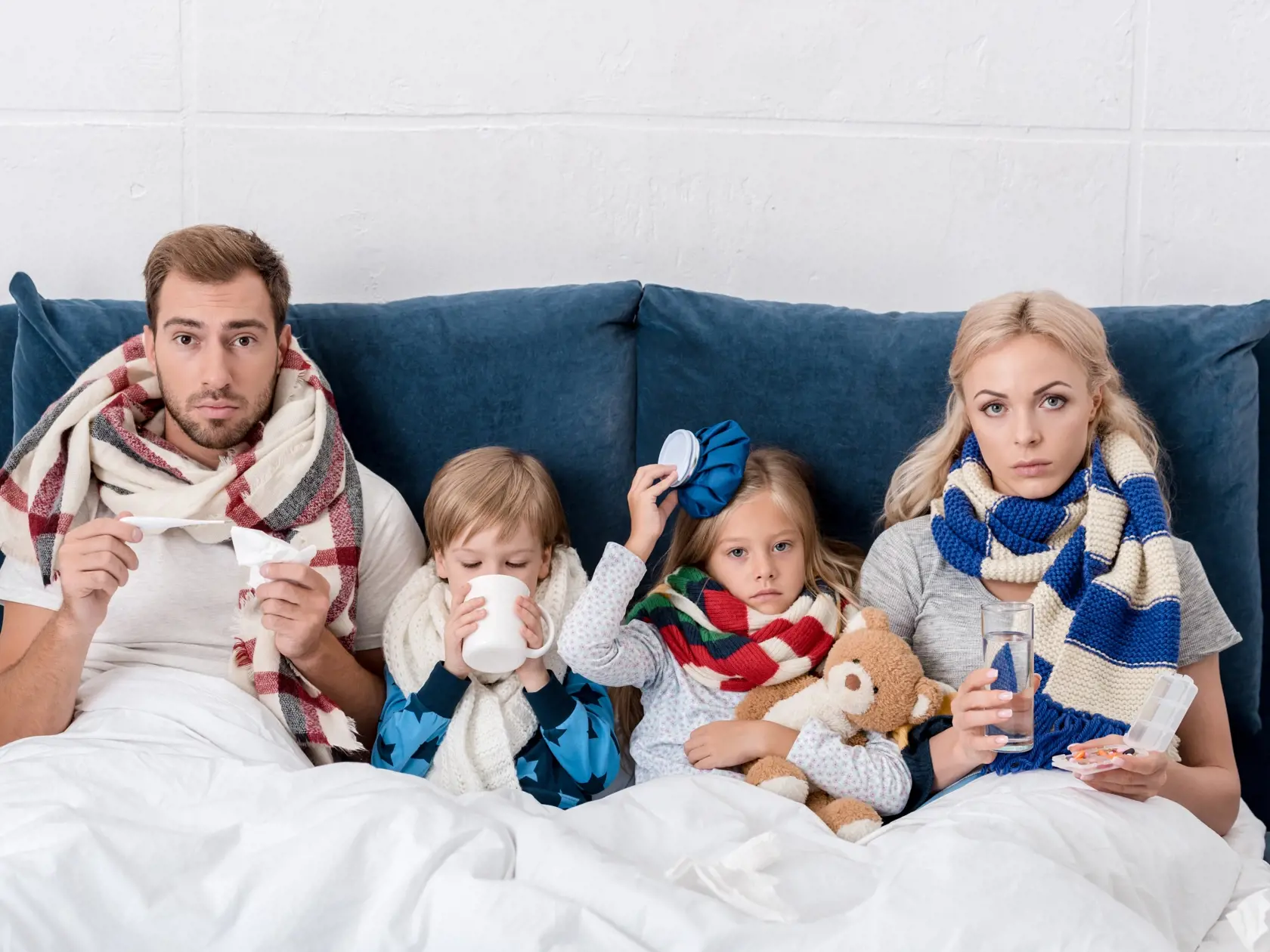Sick,Young,Family,Sitting,In,Bed,Together,And,Looking,At