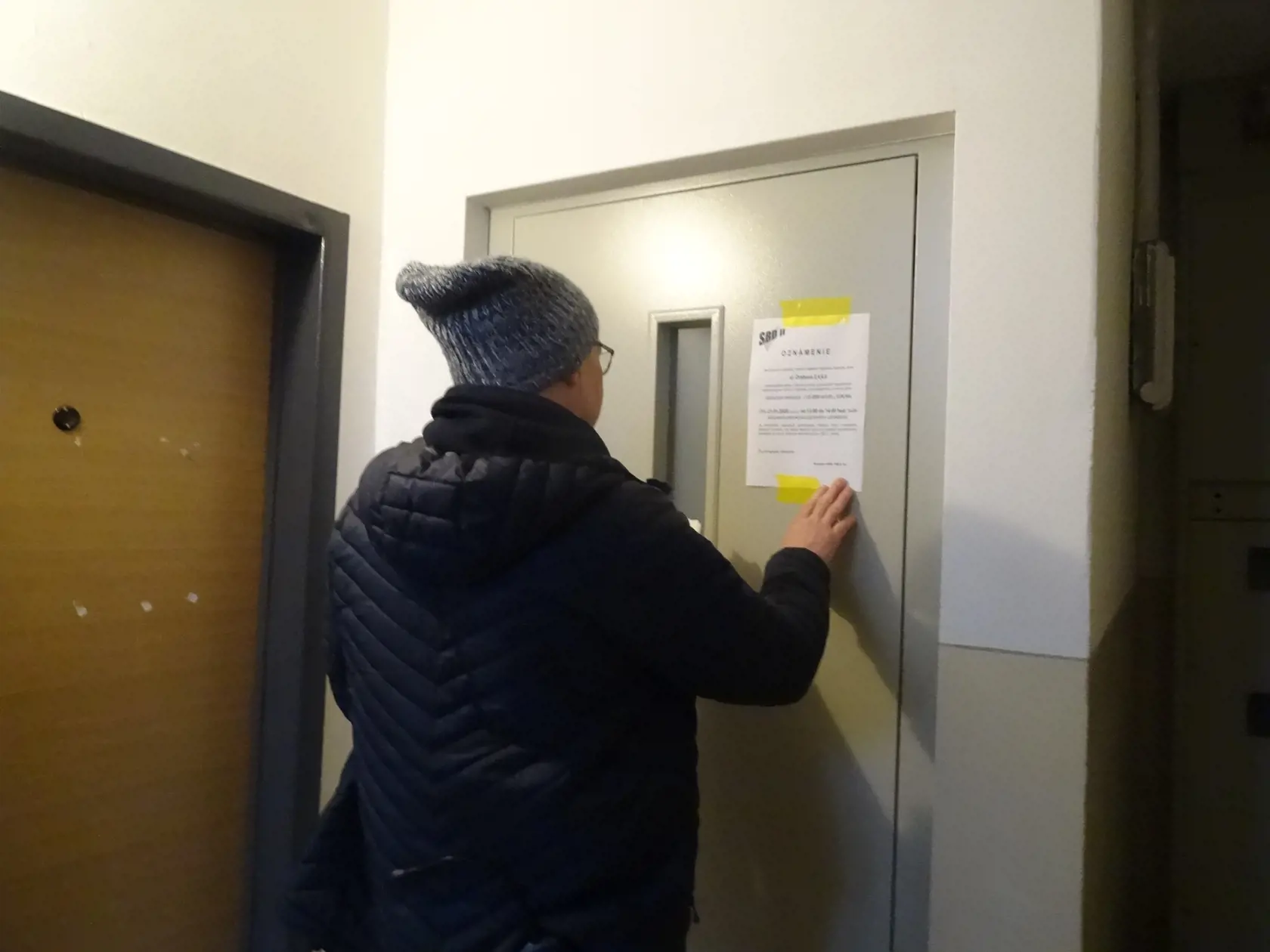 Pracovník dodávateľskej firmy lepí nový oznam.
