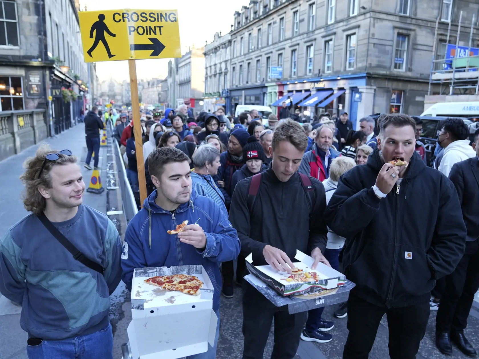 Ľudia jedia pizzu, keď čakajú v rade pred Katedrálou sv. Egídia v škótskom Edinburghu, v ktorej je vystavená rakva zosnulej britskej kráľovnej Alžbety II. v pondelok 12. septembra 2022.