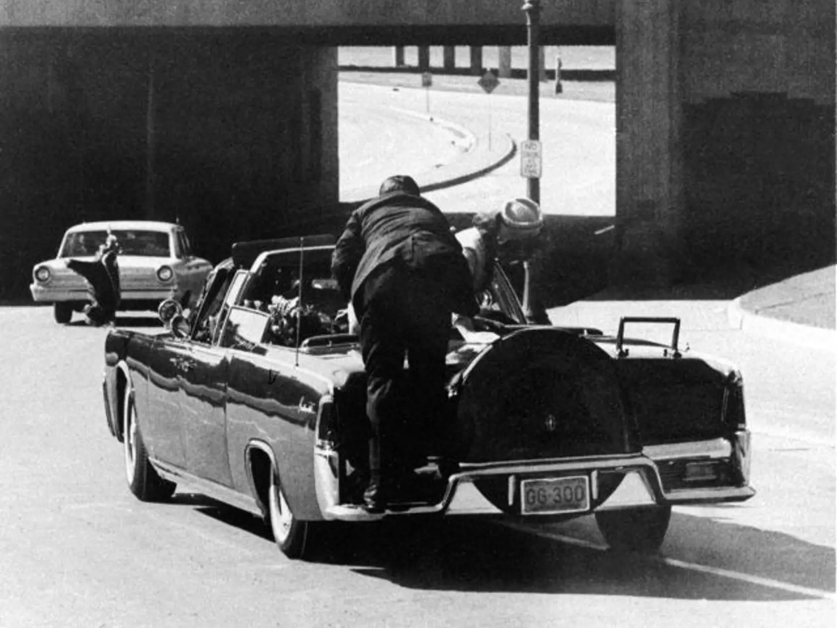 FILE - In this Friday, Nov. 22, 1963 file photo, President John F. Kennedy slumps down in the back seat of the Presidential limousine as it speeds along Elm Street toward the Stemmons Freeway overpass in Dallas after being fatally shot. First lady Jacqueline Kennedy leans over the president as Secret Service agent Clint Hill pushes her back to her seat. "She's going to go flying off the back of the car," Hill thought as he tried to secure the first lady. (AP Photo/James W. "Ike" Altgens)