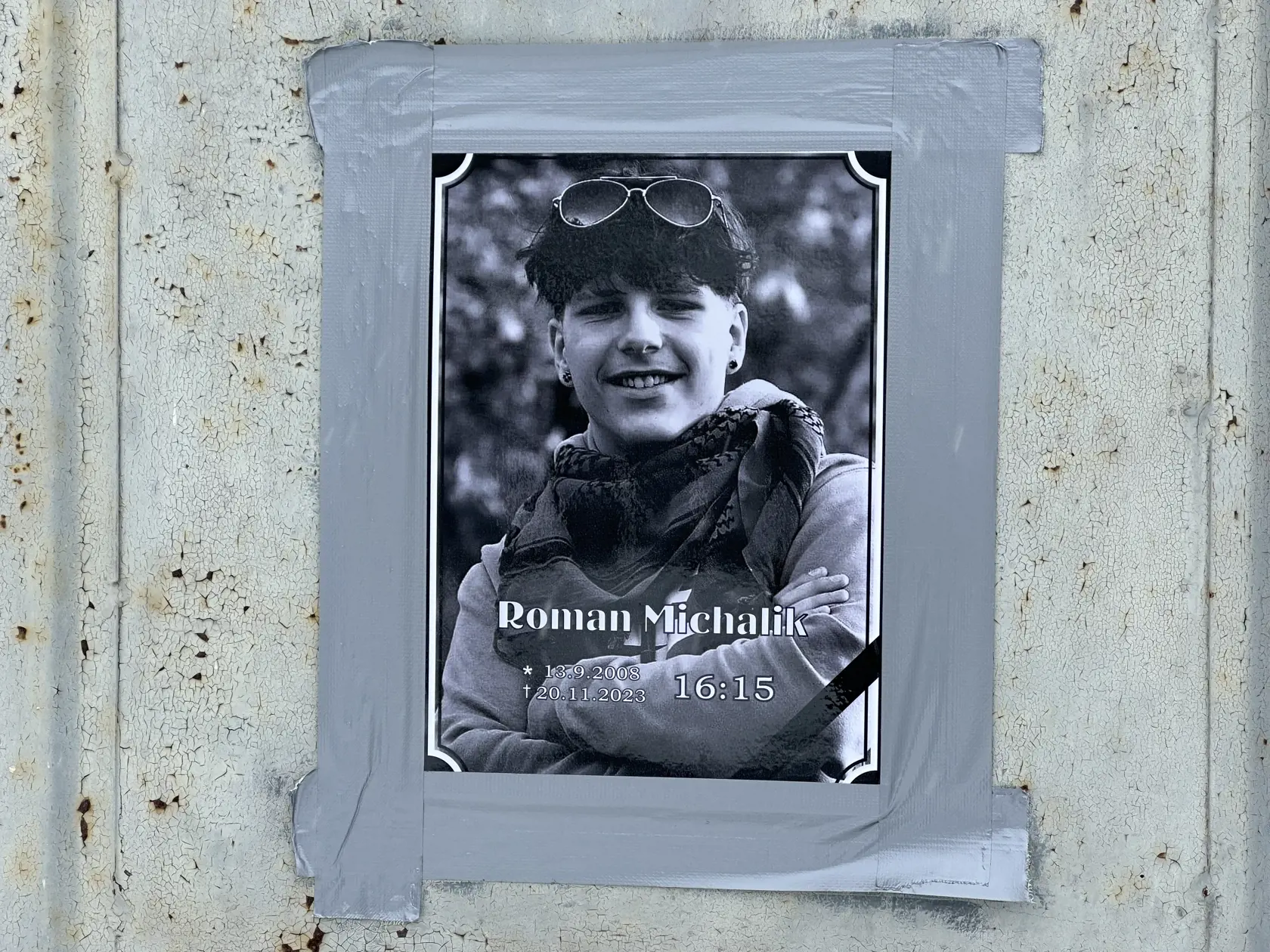 Na opotrebovaných dverách pri mieste, kam Roman dopadol, je prilepená jeho fotka.