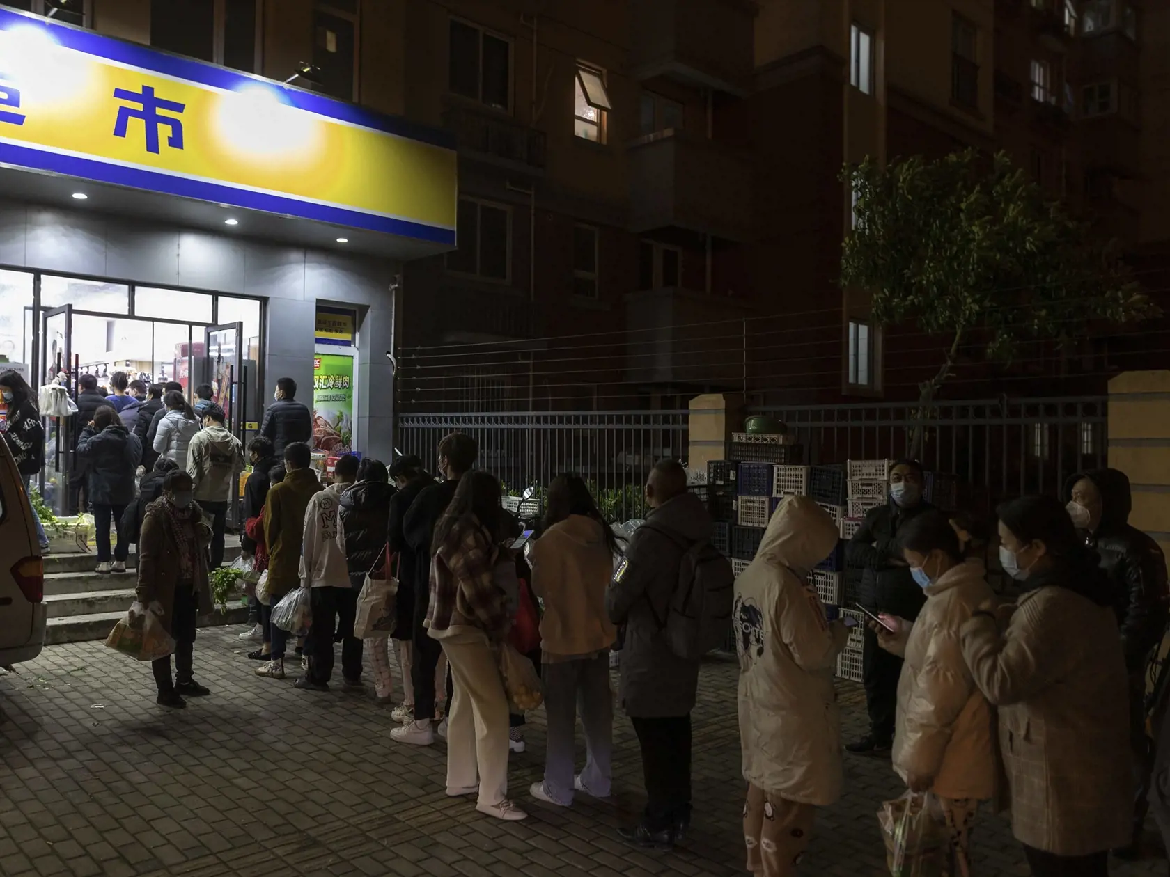 KK66 Šanghaj - Ľudia v ochranných rúškach stoja v rade pred supermarketom počas nočného nákupu potravín v Šanghaji 28. marca 2022. Najrozsiahlejší lockdown v Číne za uplynulé dva roky sa v pondelok začal v meste Šanghaj. V rámci neho chcú hromadne otestovať obyvateľov a zastaviť tak rastúci počet prípadov ochorenia COVID-19 spôsobený variantom omikron. FOTO TASR/AP
Residents wearing face masks to help protect from the coronavirus line up outside a supermarket at night to buy groceries on Sunday,