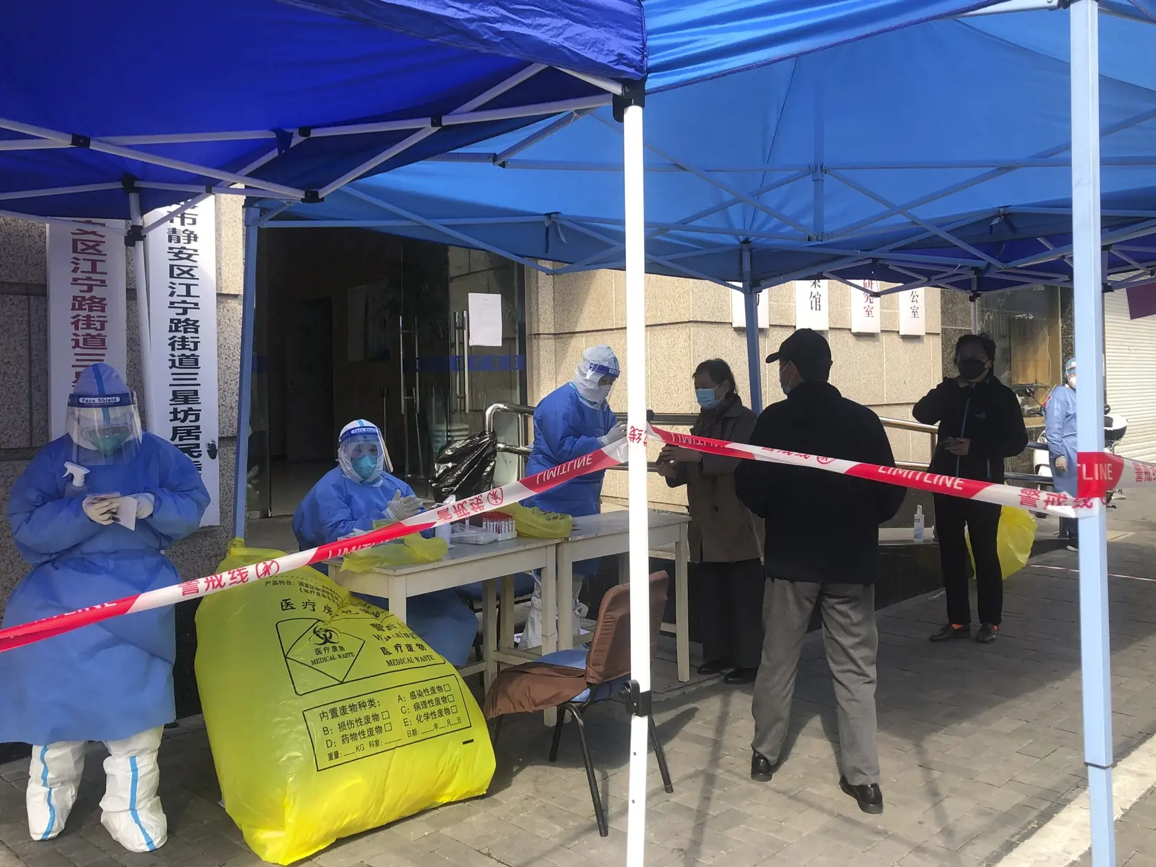 JB 12 Šanghaj - Pracovníci v ochranných odevoch  počas prvého kola masového testovania na ochorenie COVID-19 počas lockdownu v štvrti Jingan, v západnej časti čínskeho Šanghaja 1. apríla 2022. Úrady v Šanghaji začali v stredu uzatvárať niektoré oblasti na západe tohto najľudnatejšieho čínskeho mesta o dva dni skôr, ako pôvodne plánovali. Dôvodom pre lockdown je rýchle šírenie nového koronavírusu, ktorým sa za uplynulý deň nakazilo rekordných takmer 6000 osôb. Obyvatelia Šanghaja sú počas lockdow