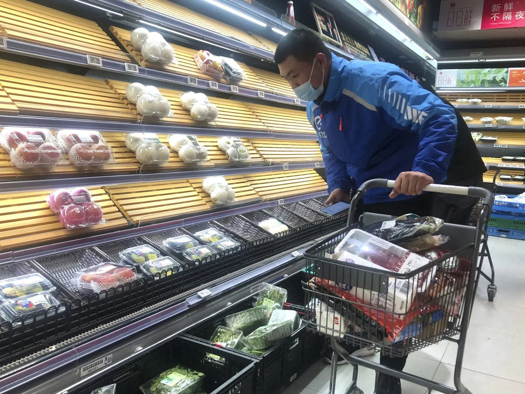JB 11 Šanghaj - Roznášač jedla vyberá veci z poloprázdnych regálov v supermarkete v čínskom Šanghaji 30. marca 2022. Úrady v Šanghaji začali v stredu uzatvárať niektoré oblasti na západe tohto najľudnatejšieho čínskeho mesta o dva dni skôr, ako pôvodne plánovali. Dôvodom pre lockdown je rýchle šírenie nového koronavírusu, ktorým sa za uplynulý deň nakazilo rekordných takmer 6000 osôb. TASR o tom informuje na základe správy agentúry Reuters. FOTO TASR/AP

A delivery man selects items from partial