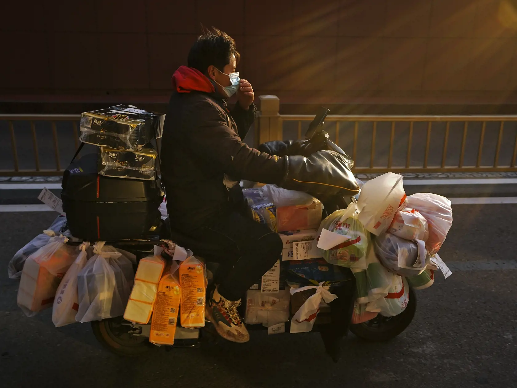 WA 32 Peking - Pracovník donáškovej služby s ochranným rúškom na tvári proti šíreniu ochorenia COVID-19 priváža na motorke zákazníkom objednávky v Pekingu v stredu 4. januára 2023. Svetová zdravotnícka organizácia (WHO) je "znepokojená" nárastom počtu prípadov ochorenia COVID-19 v Číne, uviedol v stredu generálny riaditeľ WHO Tedros Adhanom Ghebreyesus. Zároveň opäť vyzval Peking, aby poskytoval rýchle a pravidelné údaje o hospitalizáciách a úmrtiach. FOTO TASR/AP


A delivery worker adjusts his