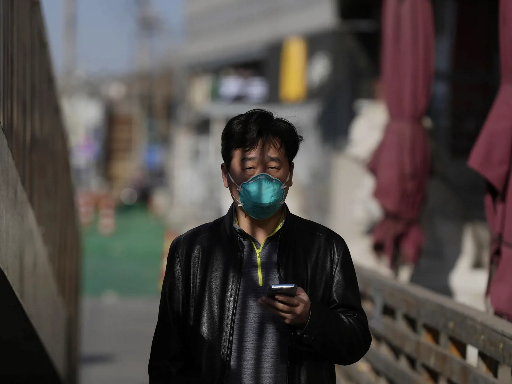 Na archívnej snímke z 8. decembra 2022 muž s respirátorom na tvári a mobilným telefónom v ruke kráča ulicami v Pekingu. Čína oznámila, že od utorka 13. decembra ukončí prevádzku mobilnej aplikácie, určenej na sledovanie kontaktov v kontexte šírenia ochorenia Covid-19.  Čína pristupuje k tomuto kroku len niekoľko dní po tom, čo oznámila koniec rozsiahlych lockdownov a povinnej karantény v štátnych zariadeniach.