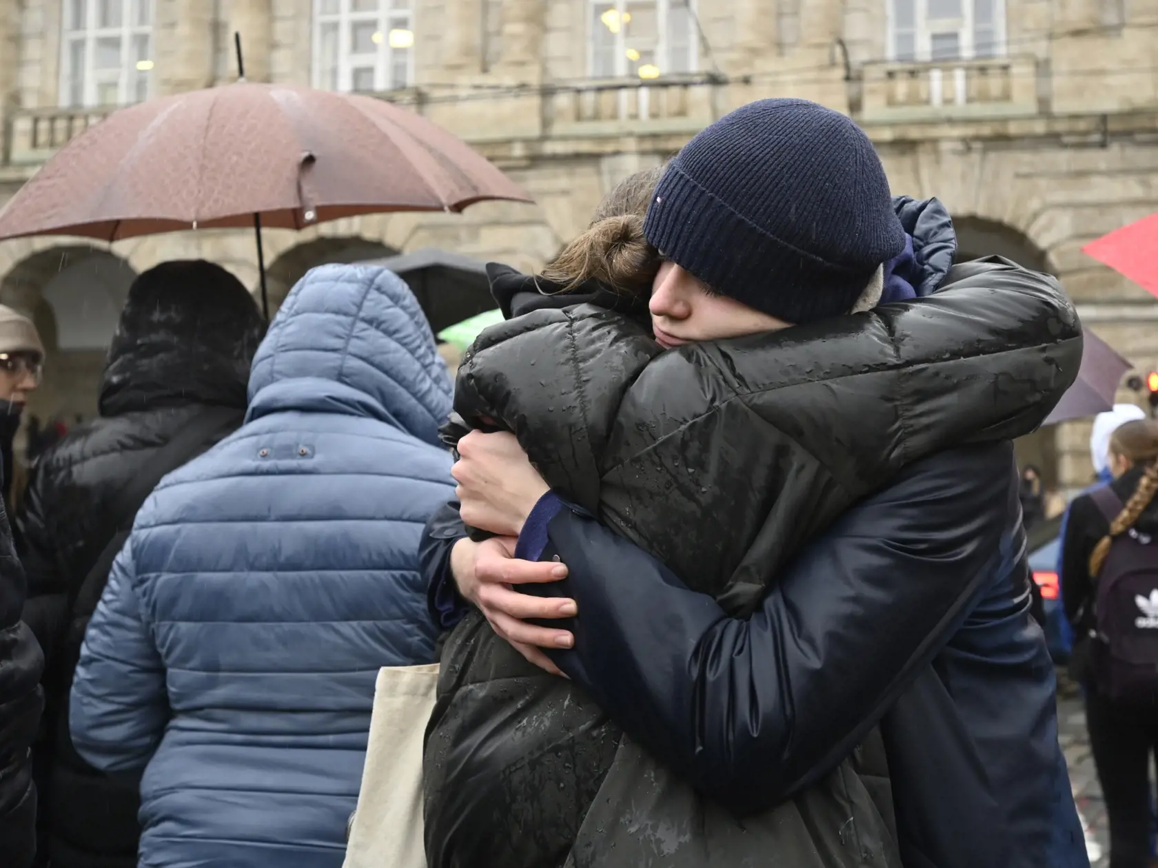 JB 62 Praha - Ľudia sa objímajú počas minúty ticha na pamiatku obetí štvrtkovej masovej streľby pred budovou Filozofickej fakulty Univerzity Karlovej (FF UK) v centre Prahy 23. decembra 2023. Česká republika si v sobotu  štátnym smútkom pripomína obete štvrtkovej streľby na Filozofickej fakulte Univerzity Karlovej v Prahe. Štátne vlajky na úradoch a inštitúciách sú spustené na pol žrde spoločne s čiernymi zástavami; na poludnie sa po celej krajine rozoznejú zvony. TASR informuje podľa správ serv