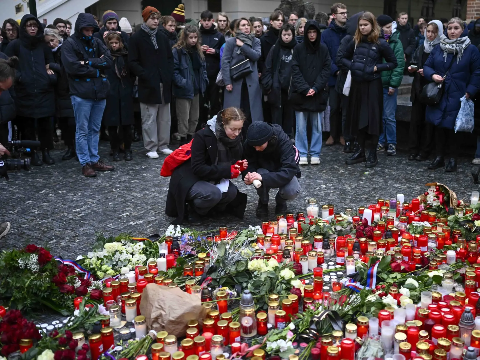 WA 17 Praha - Ľudia zapaľujú sviečky a kladú kvety na pietne miesto pred sídlo Karlovej univerzity na pamiatku obetí masovej streľby v centre Prahy v piatok 22. decembra 2023. Pri streľbe na Filozofickej fakulte Univerzity Karlovej v Prahe prišlo vo štvrtok o život 15 ľudí, vrátane strelca. Ďalších  25 osôb utrpelo zranenia. Strelec zasiahol aj troch ľudí v okolí budovy a došlo tiež k prestreleniu civilného vozidla, aj vozidla polície. FOTO TASR/AP

Mourners lay candle lights outside the headqua