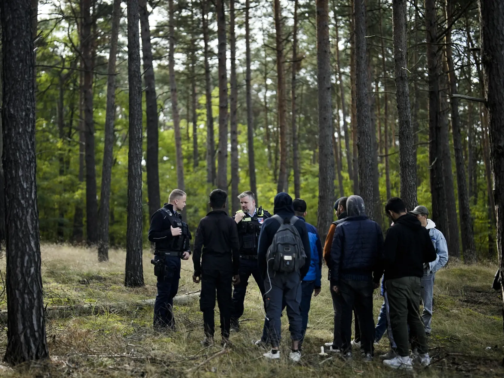 Nemecký policajt rozpráva do vysielačky, keď spolu s kolegom objavili počas hliadky v lese skupinu migrantov, ktorí nelegálne prekročili hranice z Poľska do Nemecka neďaleko obce Forst juhovýchodne od Berlína v streda 11. októbra 2023.