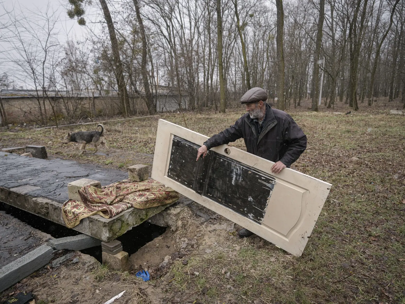 WA 65 Buča - Muž dvíha dvere zakrývajúce otvor do provizórneho otvoru, v ktorom sú podľa miestnych obyvteľov telá civilistov zabitých ruskými silami, ktoré nemohli previezť na cintorín v ukrajinskom meste Bucha v Kyjevskej oblasti počas 39. dňa ruskej invázie na Ukrajinu v nedeľu 3. apríla 2022. Ukrajinskí a západní lídri reagovali s pobúrením na nájdenie týchto masových hrobov a niekoľkých stoviek tiel. Ukrajinský prezident Volodymyr Zelenskyj obvinil priamo Moskvu zo zabíjania civilistov. Rusk