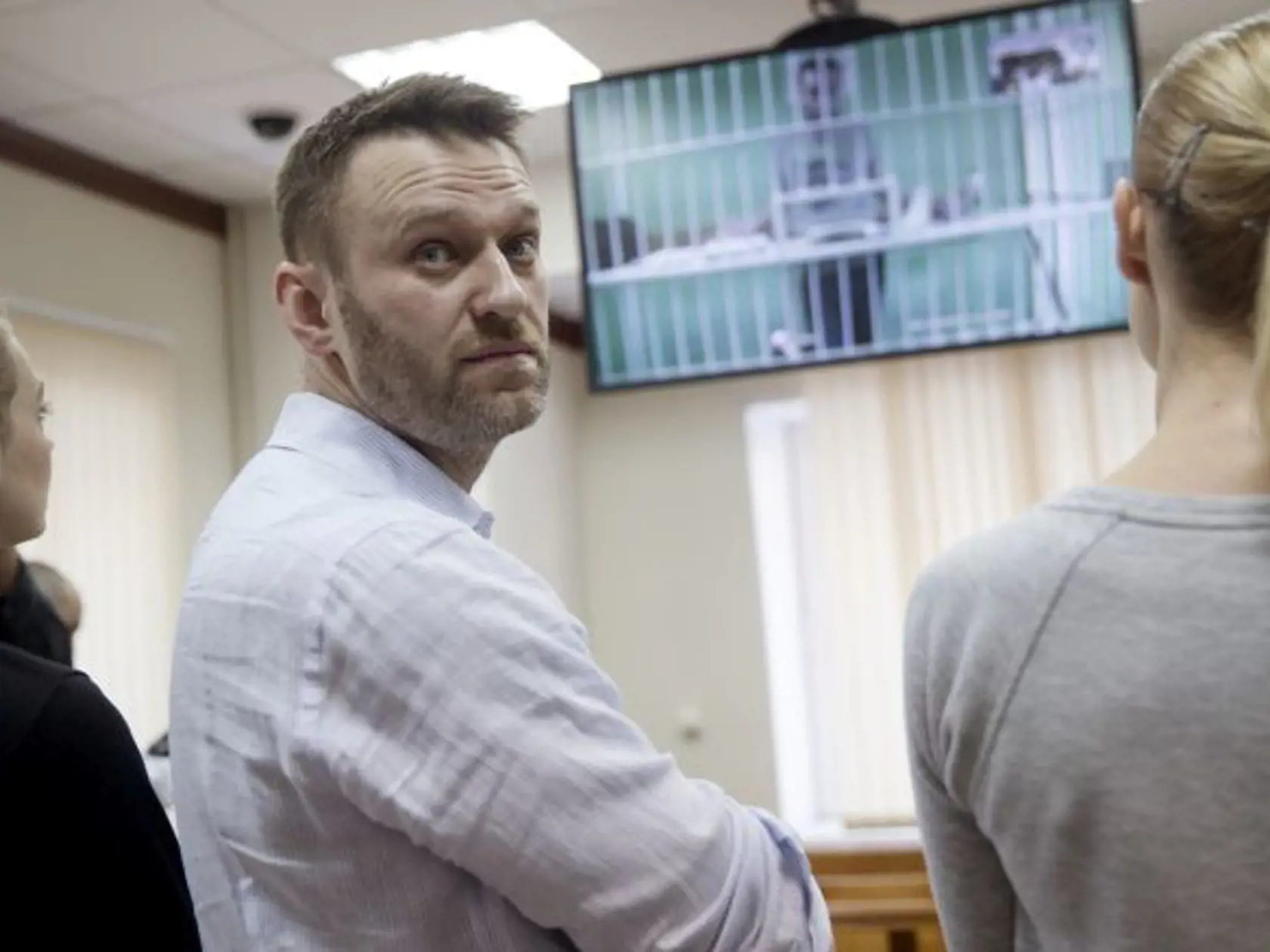 Russian opposition activist and anti-corruption crusader Alexei Navalny, center, his wife Yulia, left, and his brother Oleg's wife Victoria attend a video call with Oleg, shown on a TV screen, at a court in Moscow, Russia, Tuesday, Feb. 17, 2015. Oleg Navalny was convicted on Dec. 30, 2014 and sentenced for three and a half years. Alexei Navalny was also convicted and sentenced to the same prison term, but it was suspended. (AP Photo/Pavel Golovkin)