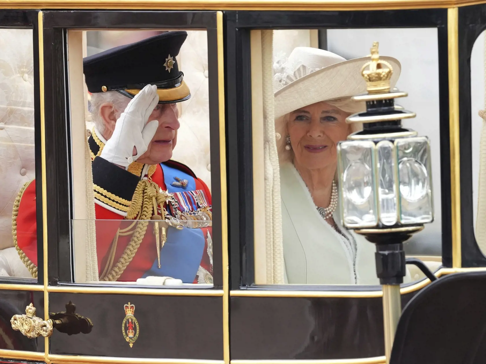 Britský kráľ Karol III. (vľavo) a britská kráľovná Kamila mávajú z koča počas príchodu navojenskú prehliadku Trooping the Colour, ktorá sa koná na počesť jeho narodenín v Londýne v sobotu 15. júna 2024. Prehliadka Trooping the Colour sa koná tradične v júni, hoci narodeniny má Karol až 14. novembra. Britskí panovníci však narodeniny oslavujú dvakrát - súkromne aj formou verejnej oslavy. FOTO TASR/AP
