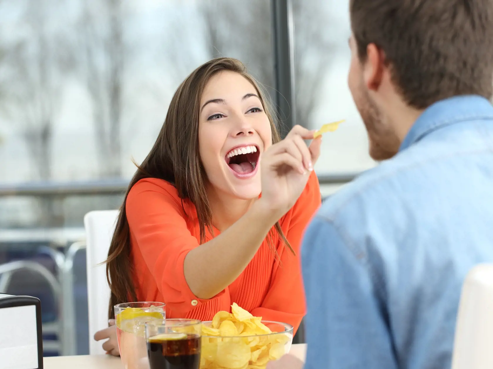 Playful,Couple,Eating,Chip,Potatoes,And,Joking,Looking,Each,Other