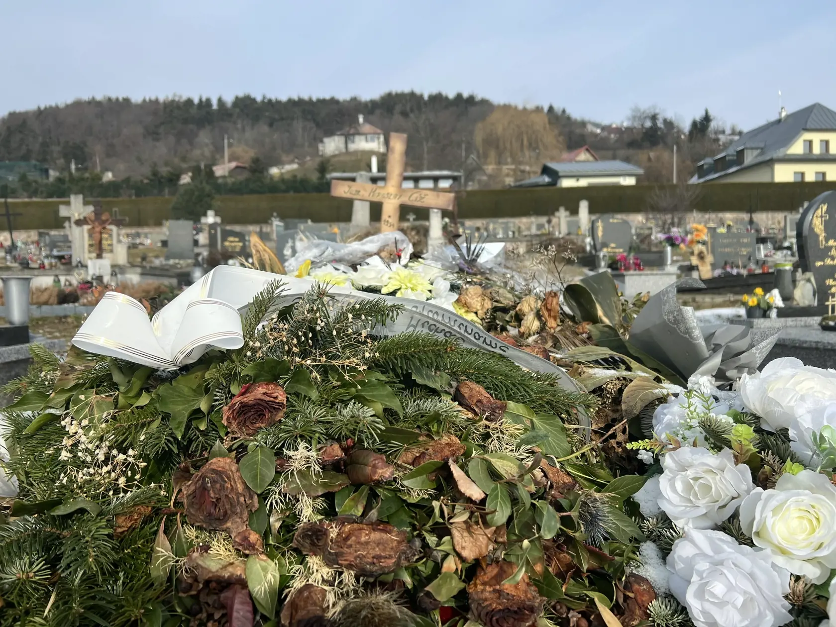 Namiesto pomníka tu dočasne stojí len jednoduchý drevený kríž a hrob pôsobí ako keby sa oň nik nestaral - ležia na ňom staré kvety ešte od pohrebu.