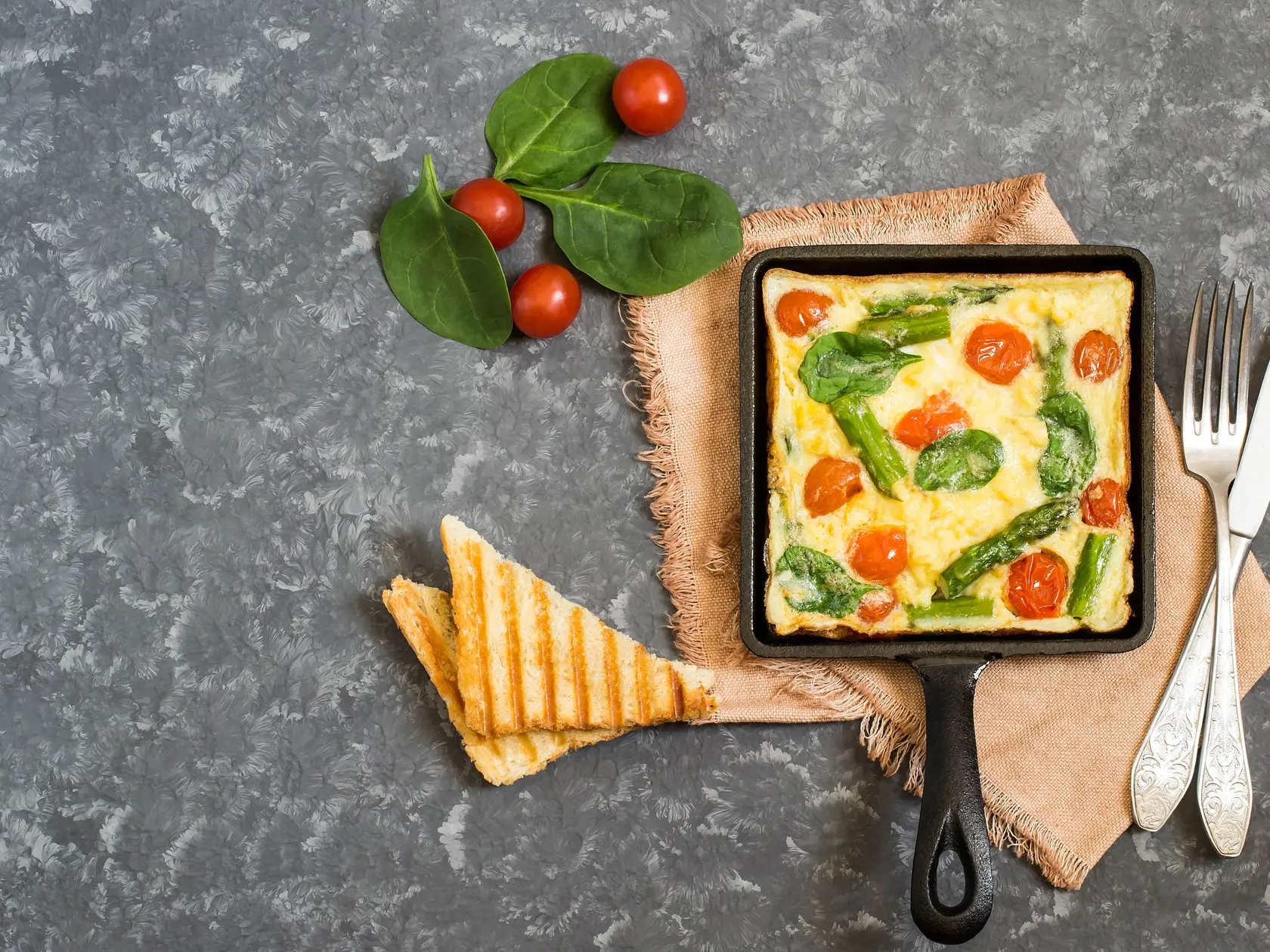 Frittata so špargľou, paradajkami a špenátom.