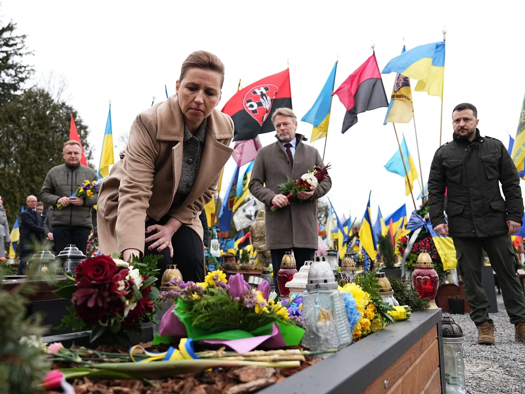 WA 46 Ľvov - Dánska premiérka Mette Frederiksenová (vľavo), jej manžel Bo Tengberg (uprostred) a ukrajinský prezident Volodymyr Zelenskyj kladú kvety počas spomienkového obradu na Marsovom poli na cintoríne v ukrajinskom Ľvove v piatok 23. februára 2024. V sobotu 24. februára uplynú dva roky od okamihu, keď ruský prezident Vladimir Putin skoro ráno v televíznom prejave oznámil začiatok vojenskej invázie na Ukrajinu. Označil ju za "špeciálnu vojenskú operáciu" s cieľom vykonať "demilitarizáciu a 