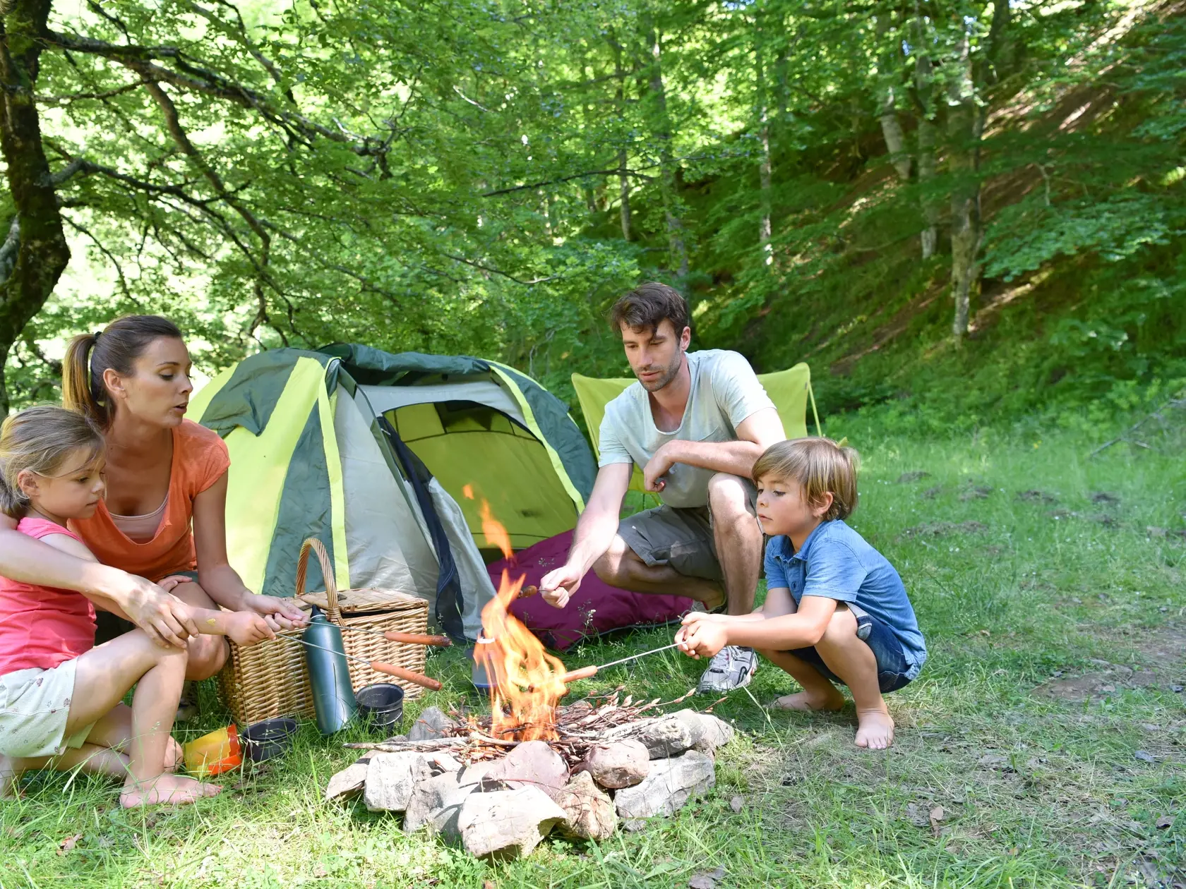 Family,Camping,And,Cooking,Sausages,In,Campfire