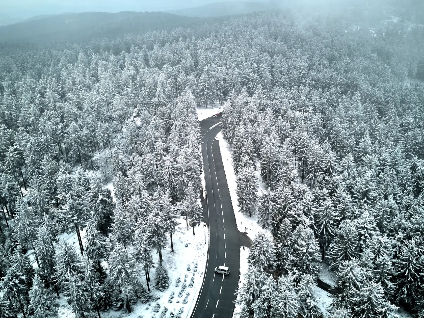 Auto sa otáča na ceste medzi zasneženými stromami v nemeckom regióne Taunus pri Frankfurte nad Mohanom 14. marca 2025.
