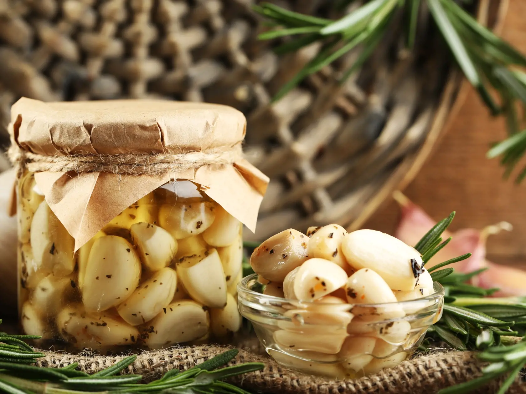 Canned,Garlic,In,Glass,Jar,And,Wicker,Mat,And,Rosemary