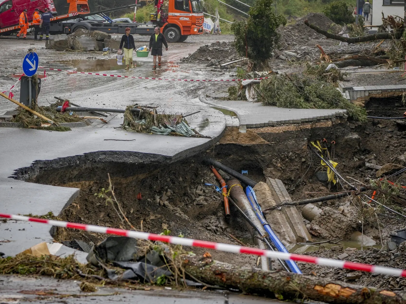 WA 47 Schuld - Ľudia si odnášajú svoje veci v záplavami zničenej obci Schuld, nemeckej spolkovej krajine Porýnie-Falcko v piatok 16. júla 2021.  Najmenej 120 ľudí zahynulo a niekoľko stoviek je nezvestných v súvislosti s prudkými dažďami a následnými povodňami, ktoré postihli v týchto dňoch západnú Európu. Najviac zasiahnutý je západ Nemecka. FOTO TASR/AP

People carry their belongings past a broken road in Schuld, Germany, Friday, July 16, 2021. Two days before the Ahr river went over the banks