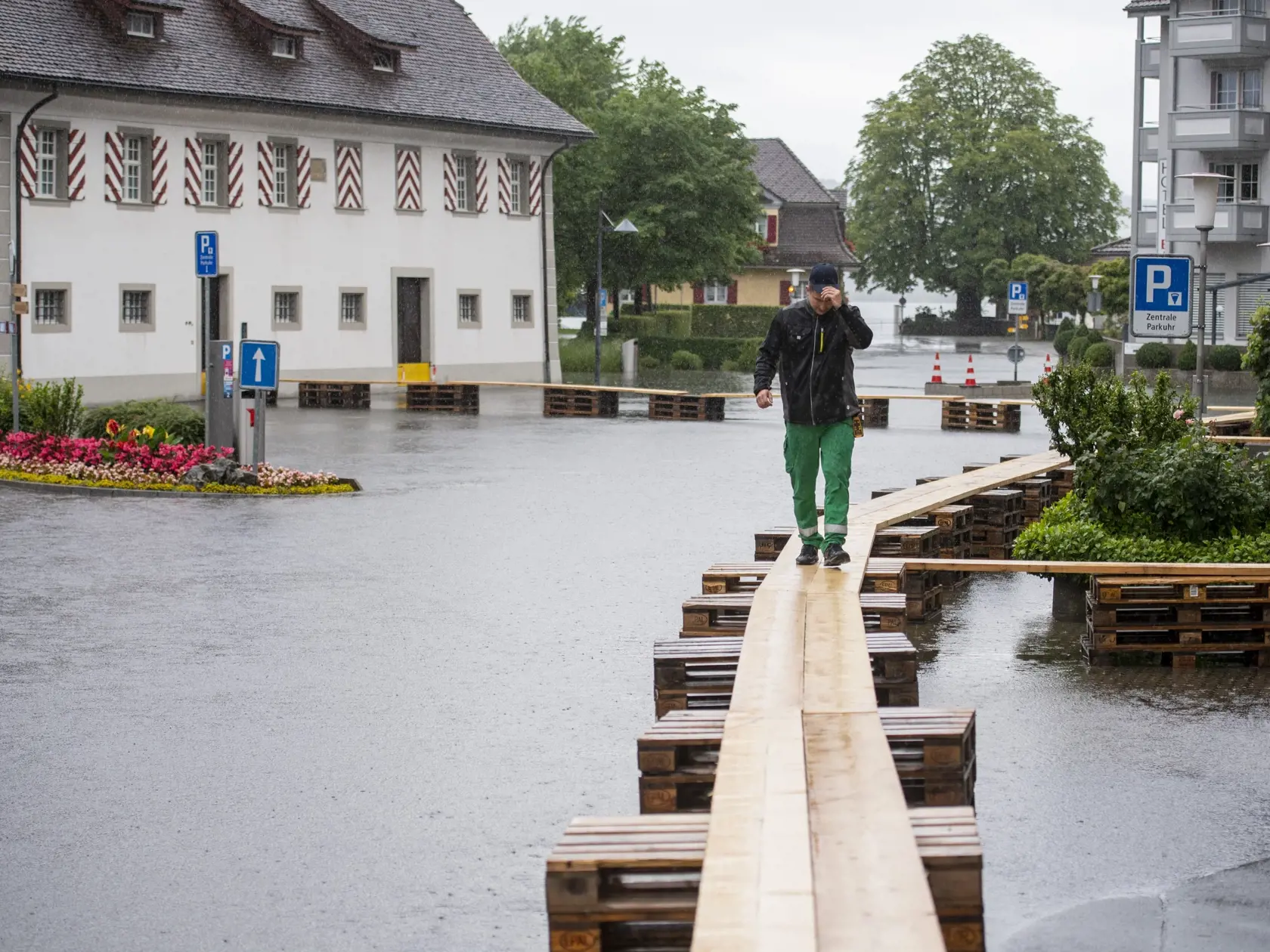 KK5 Stansstad - Na snímke muž kráča po lávke nad zaplavenýn námestím vo švajčiarskej obci Stannsad 15. júla 2021. FOTO TASR/AP
A person walks on a footbridge as the village square is covered with flood water in Stansstad at the Vierwaldstaettersee , Switzerland, Thursday, July 15, 2021.  (Urs Flueeler/Keystone via AP)