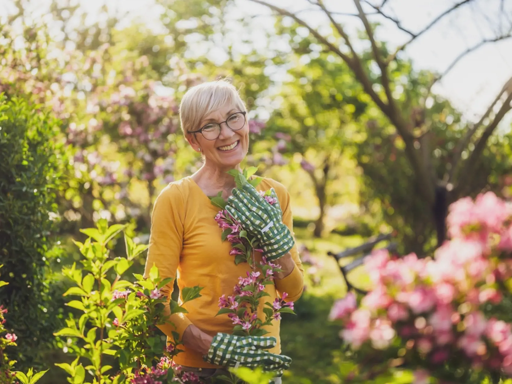 Happy,Senior,Woman,Enjoys,Looking,At,Flowers,In,Her,Garden.