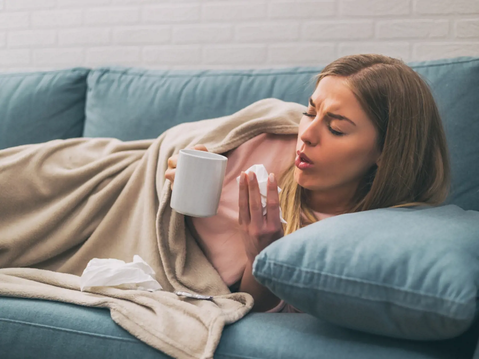 Exhausted,Woman,Coughing,And,Drinking,Tea,While,Having,Fever.image,Is