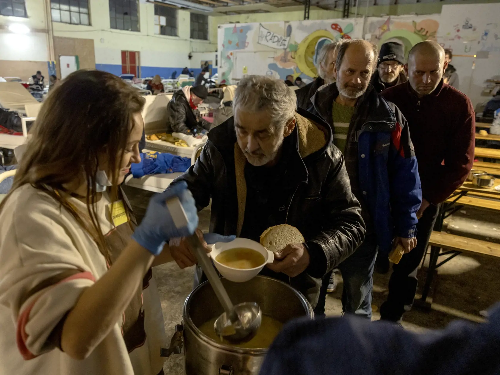 Klienti nocľahárne si po dlhom a mrazivom dni vychutnávajú teplú večeru.