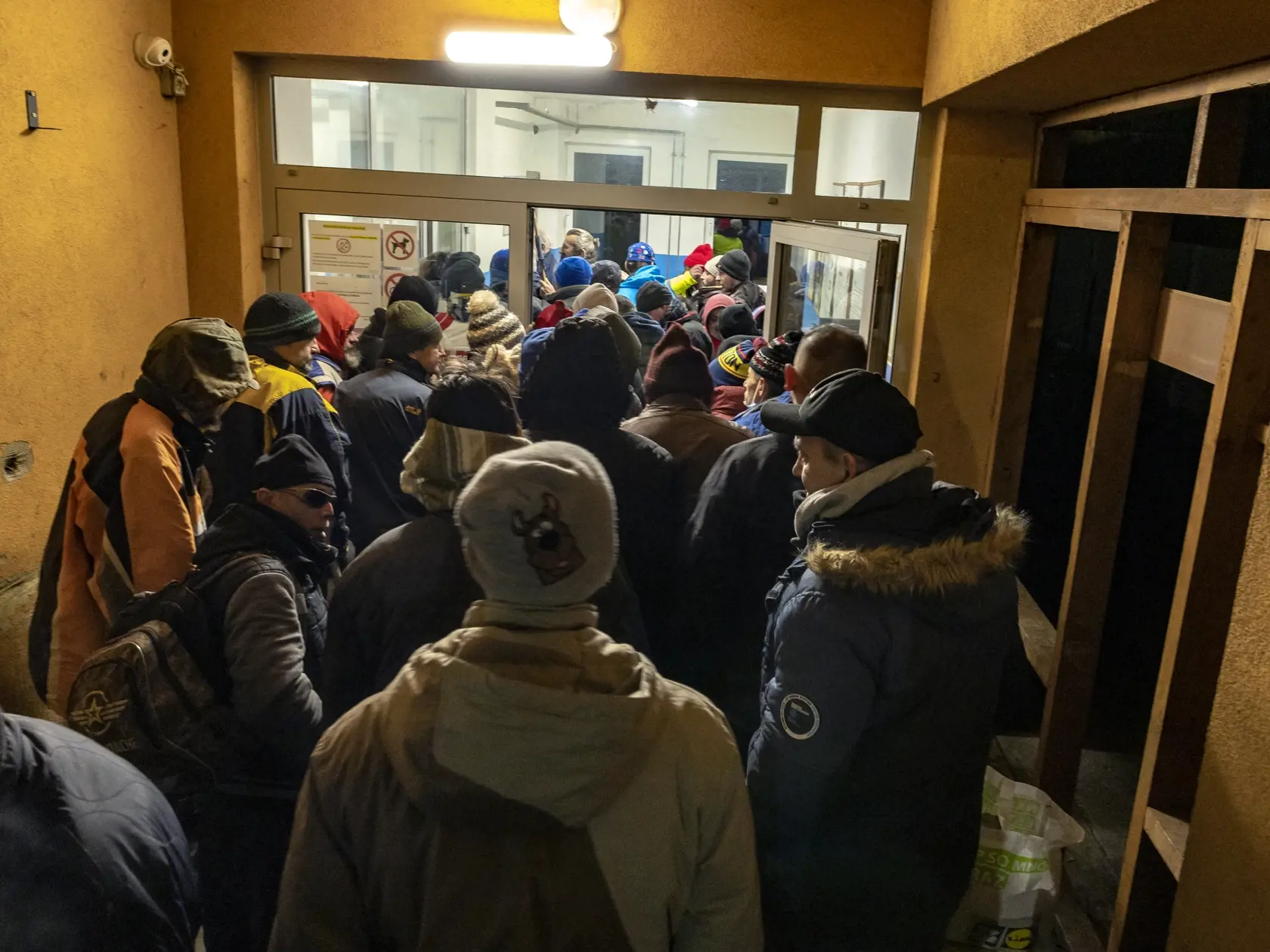 Klienti čakajú, kým sa dvere nocľahárne konečne otvoria.