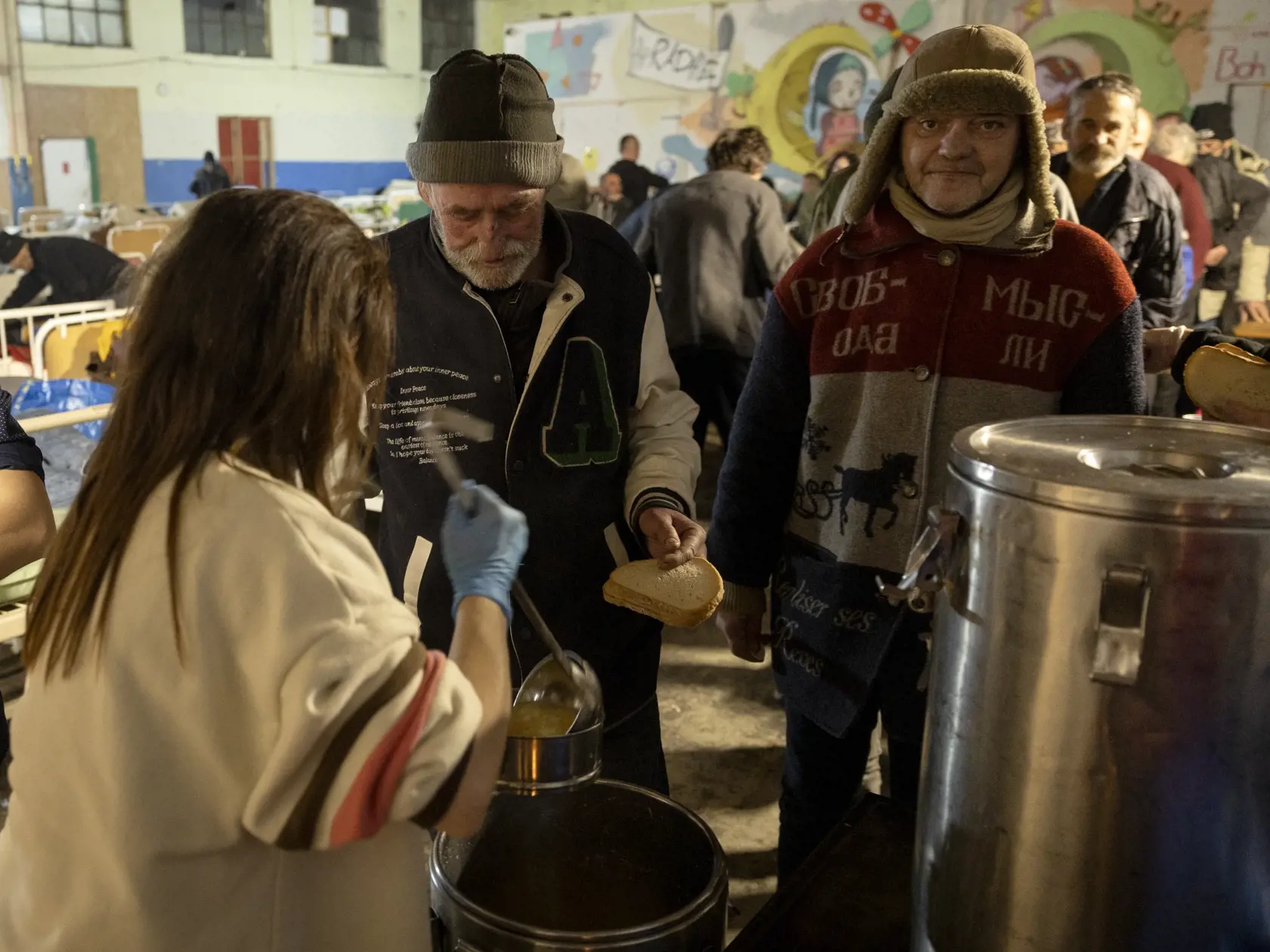 Klienti nocľahárne si po dlhom a mrazivom dni vychutnávajú teplú večeru.