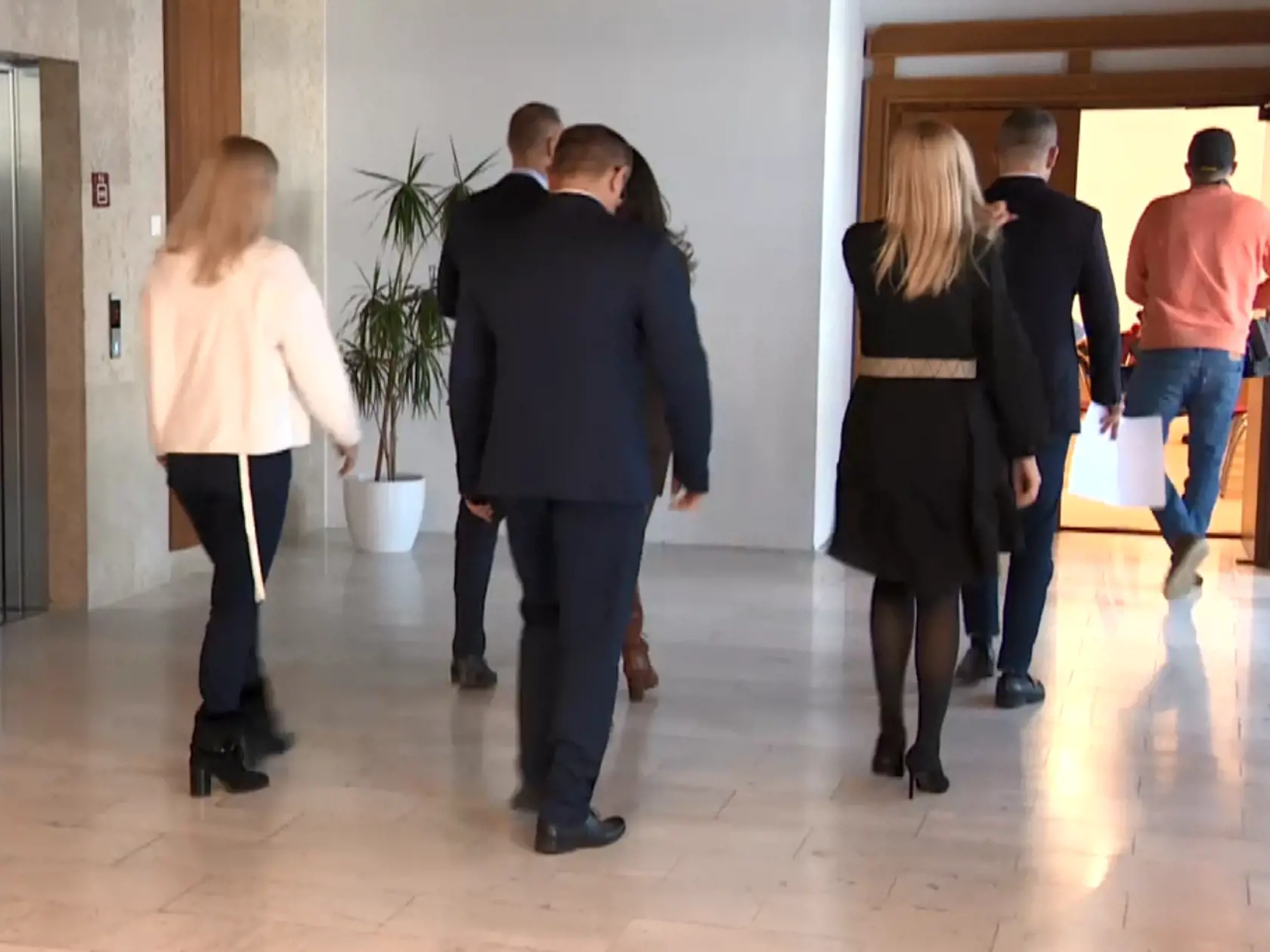 Pri vstupe do priestoru, kde sa zvyknú konať konferencie. Vpredu v ružovom pulóvri šprintuje kameraman istej televízie.