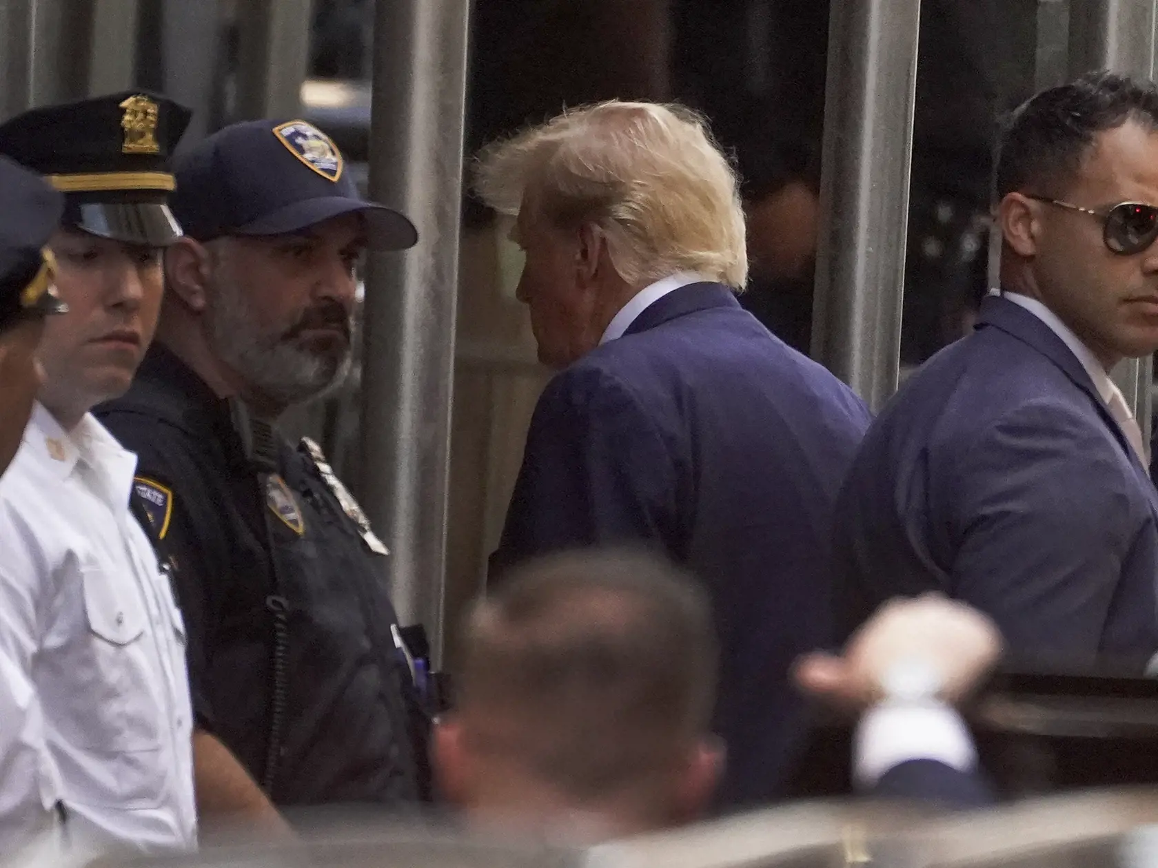 Na snímke uprostred bývalý americký prezident Donald Trump prichádza do kancelárie okresného prokurátora na Manhattane odovzdať odtlačky prstov a biometrické údaje v utorok 4. mája 2023.
