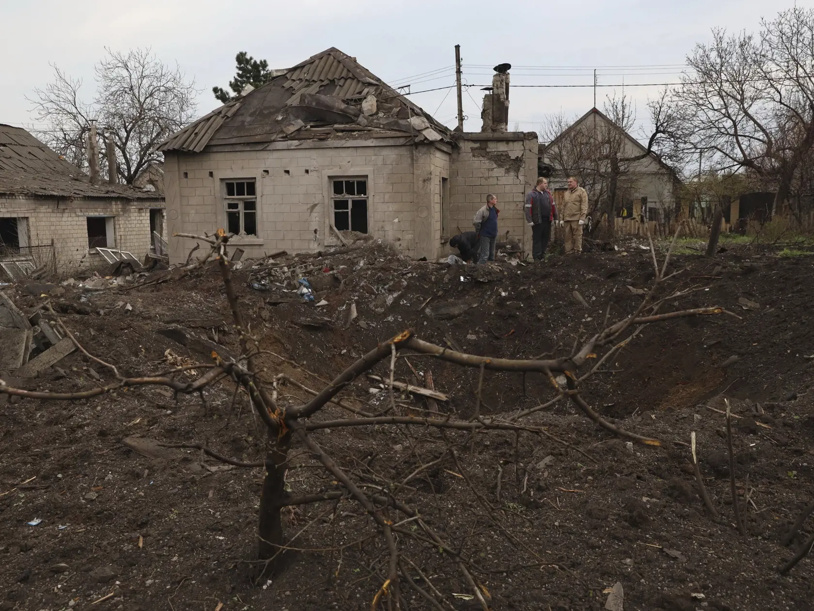 Miestni obyvatelia stoja pri obrovskom jame, ktorá zostala po ruskom raketovom útoku na obytnú budovu v ukrajinskom meste Záporožie v nedeľu ráno 9. apríla 2023. Pri útoku zahynul 50-ročný muž a jeho 11-ročná dcéra.