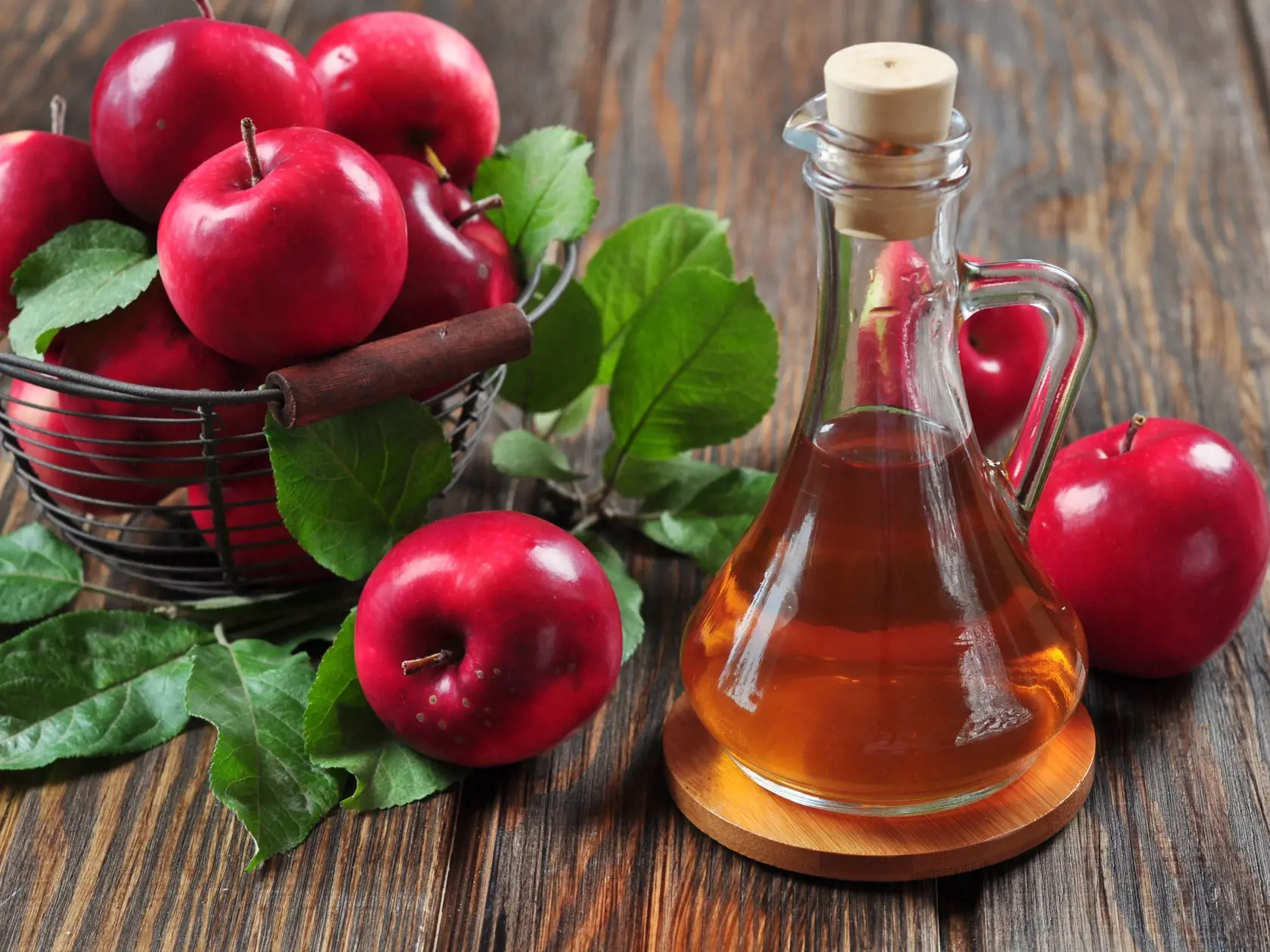 A bottle of apple cider vinegar and a bucket of apples