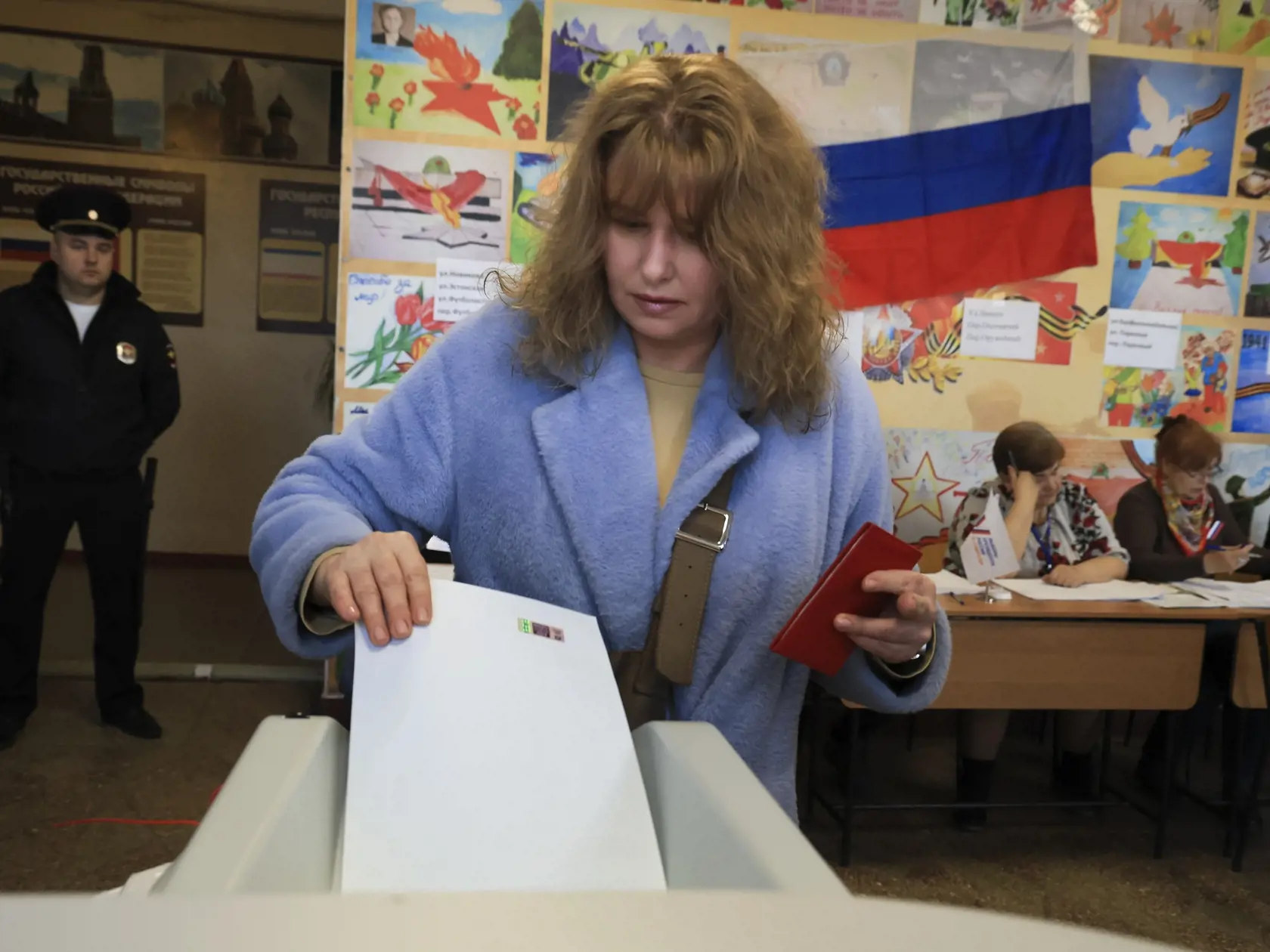 Na snímke volička vkladá obálku do volebnej schránky vo  volebnej miestnosti počas prezidentských volieb v Simferopole na Kryme v piatok 15. marca 2024.
