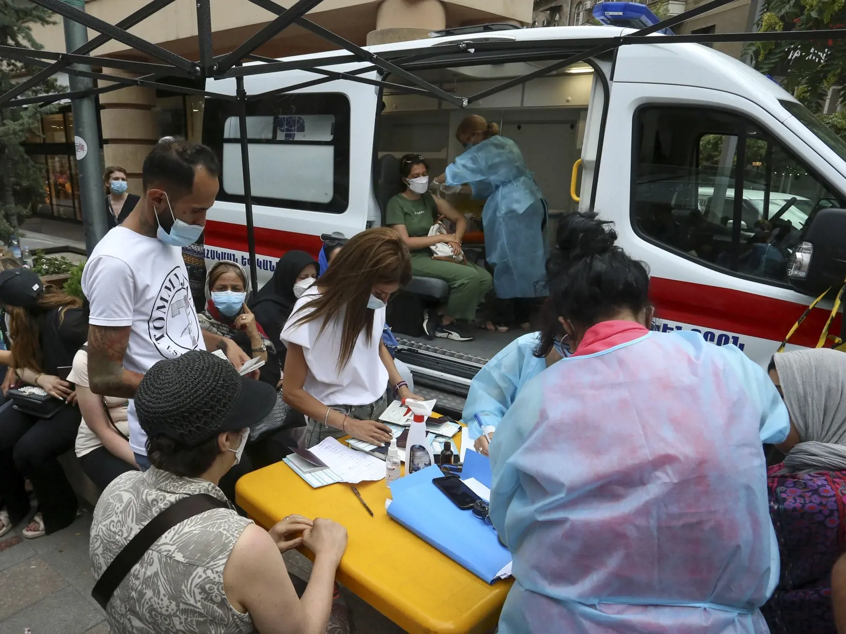 Ľudia, ktorí prevažne pochádzajú z Iránu, čakajú na očkovanie vakcínou proti ochoreniu Covid-19 v mobilnom očkovacom centre v Jerevane 14. júla 2021. Ľudia zaplnili ulice arménskeho hlavného mesta, aby dostali bezplatnú vakcínu proti koronavírusu. Od piatka môžu cudzinci dostať iba vakcíny od firmy AstraZeneca na piatich mobilných očkovacích miestach v Jerevane.