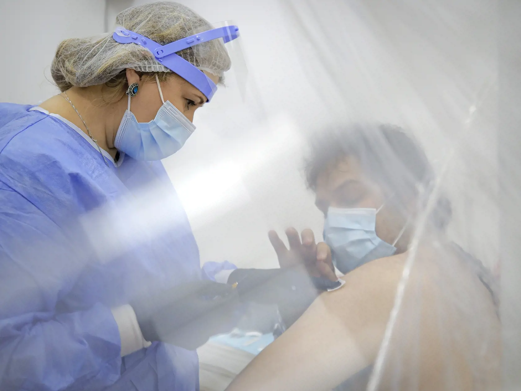 Zdravotníčka podáva mužovi vakcínu proti ochoreniu COVID-19 od spoločnosti AstraZeneca počas očkovania vo vakcinačnom centre.